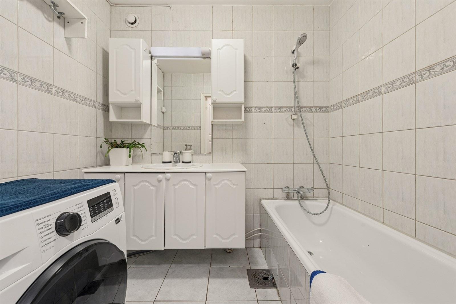 Badet er flislagt og utstyrt med badekar, opplegg for vaskemaskin og varme i gulvet. Galleribilde