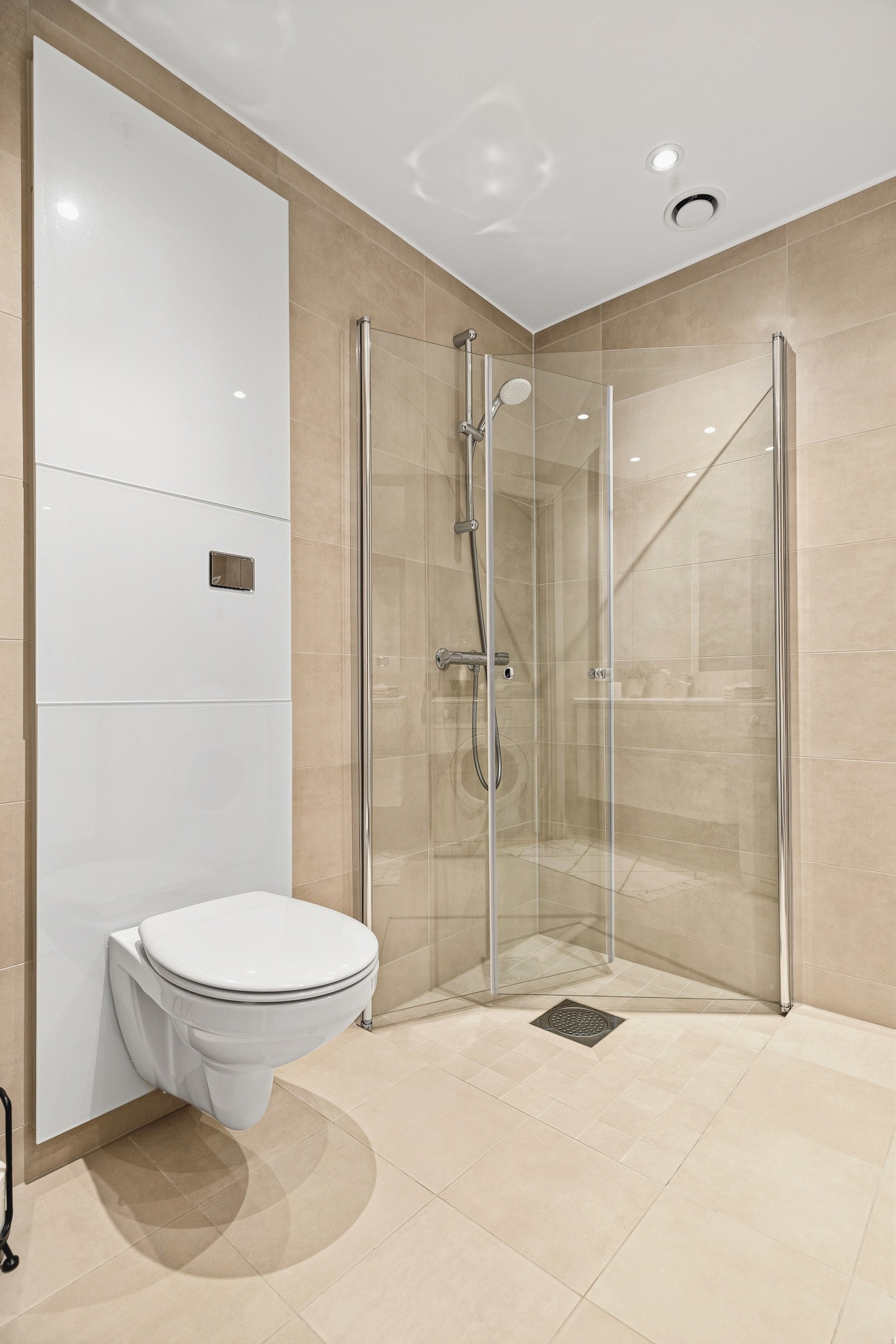 Vegghengt toalett og store fliser gir et moderne og lett utrykk Galleribilde