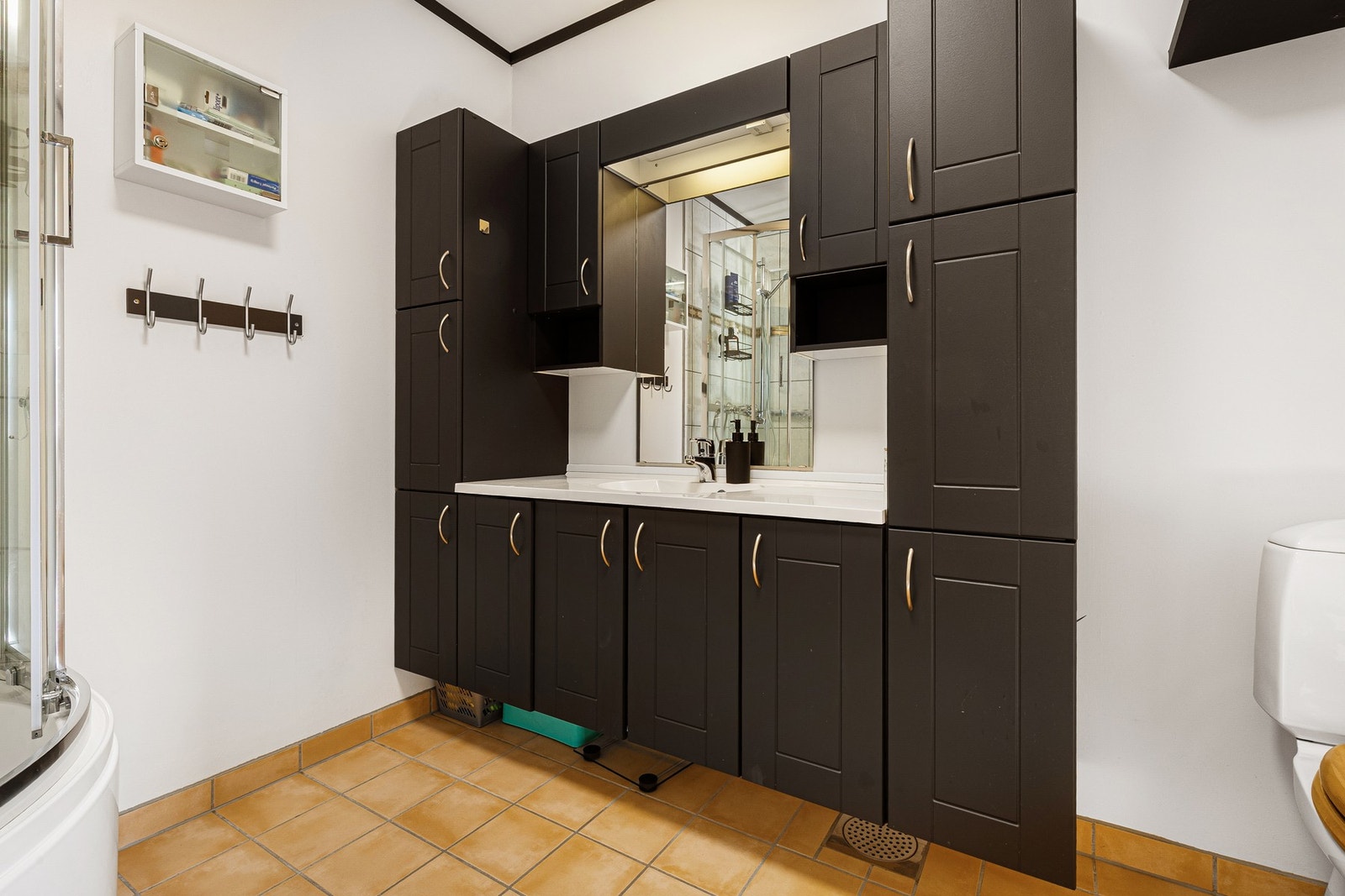 Bad har dusjkabinett med dypt kar, gulvmontert toalett og innredning med servant i helstøpt platetopp. Galleribilde