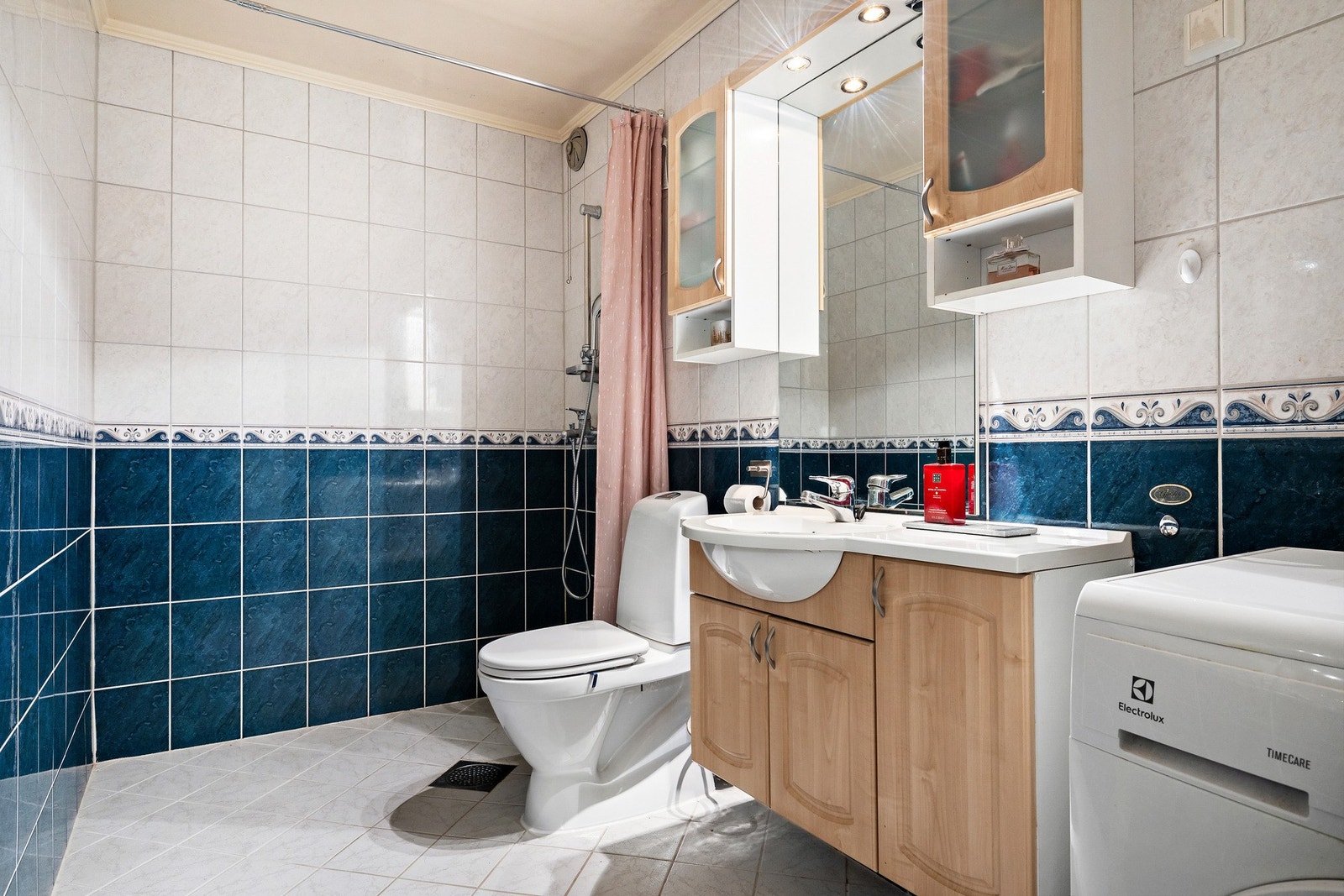 Flislagt bad med dusjhjørne, vegghengt toalett og servant i innredning. Galleribilde