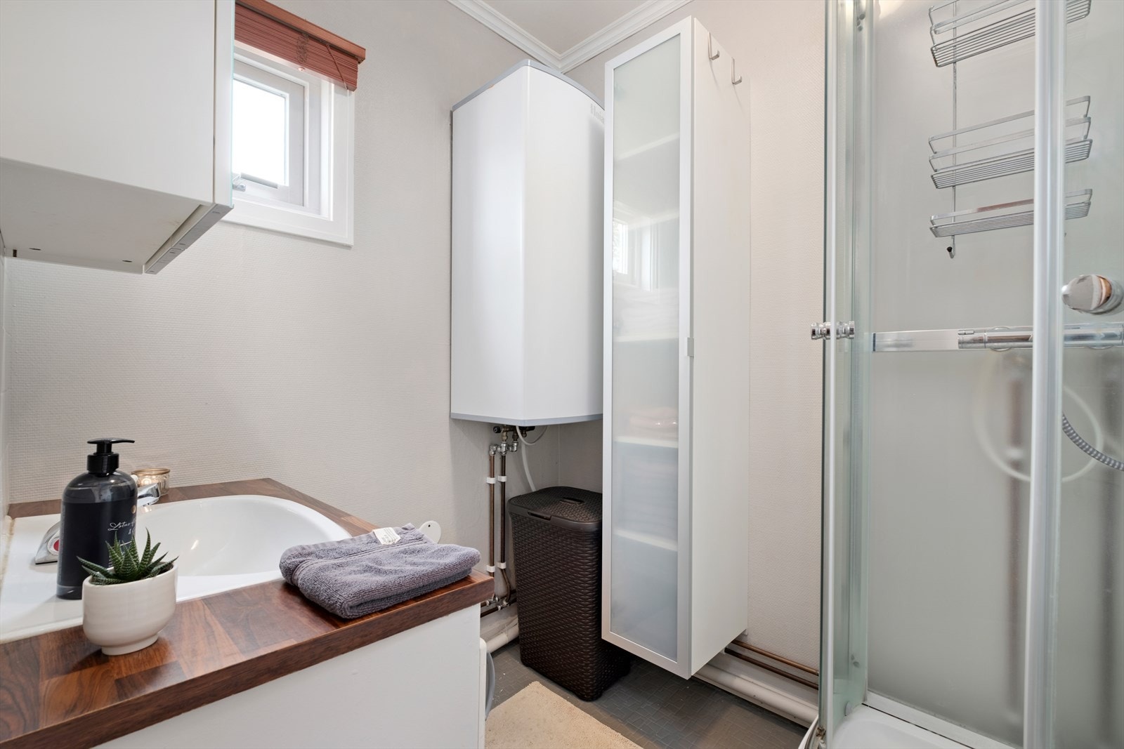 Badet i 2. etasje byr på dusjkabinett og veggmontert innredet servant. I tillegg til varmvannsberederen her er det også en bereder i kjelleren. Galleribilde