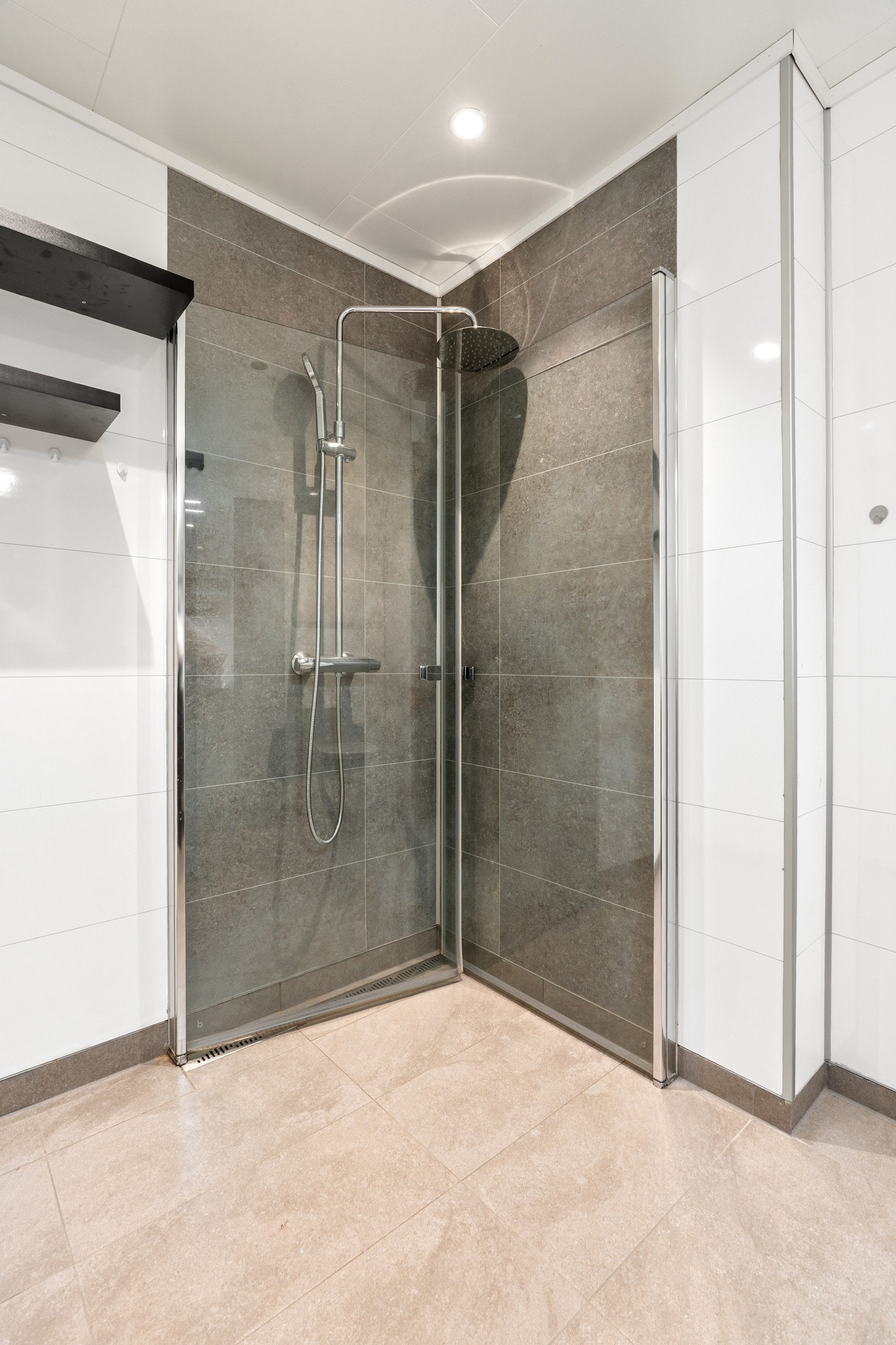 Badet har dusjhjørne med innfellbare glassdører, regndusj og hånddusj.