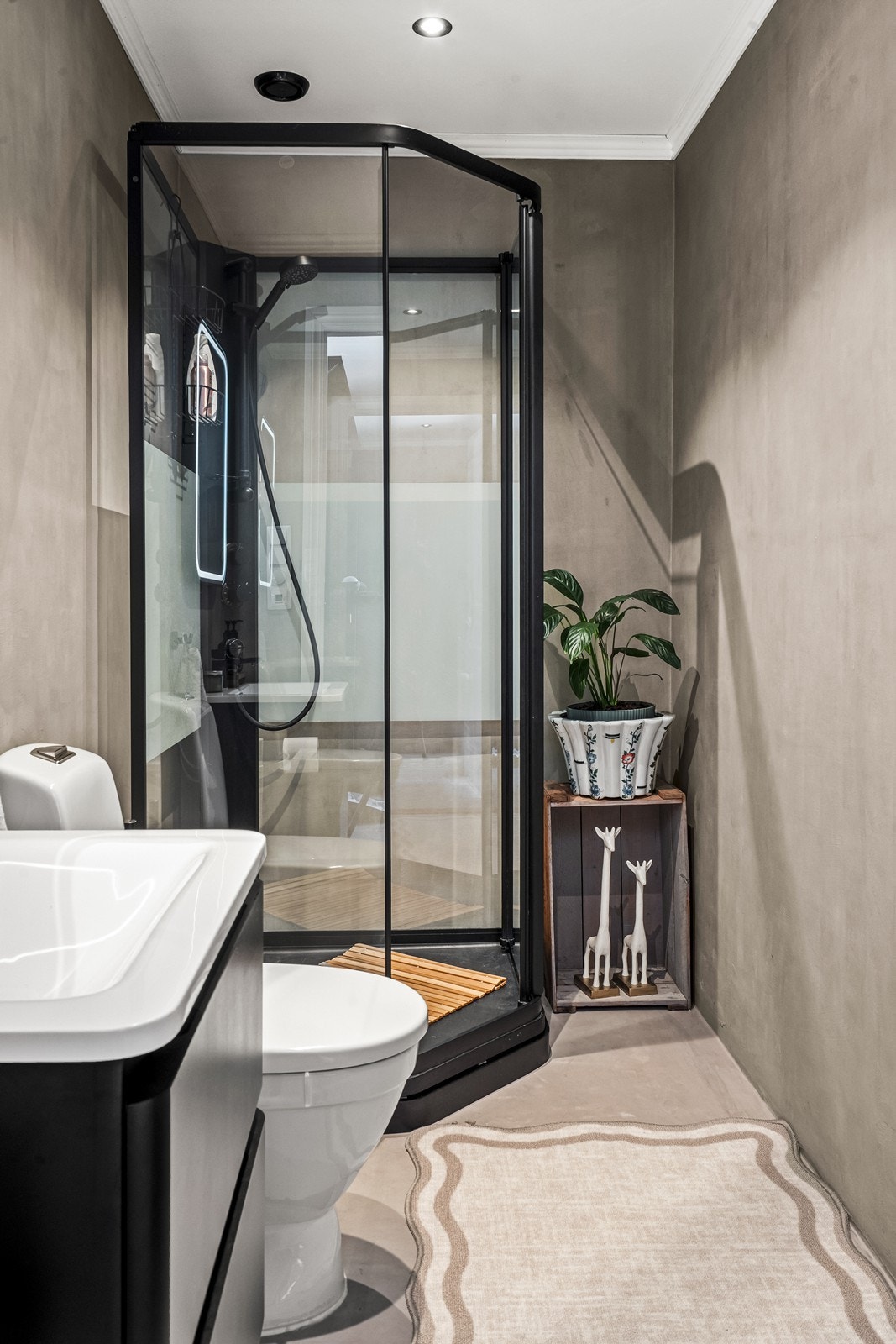 Bad i 1. etasje med dusjkabinett, toalett og servant med skap og overhengende speil. Galleribilde