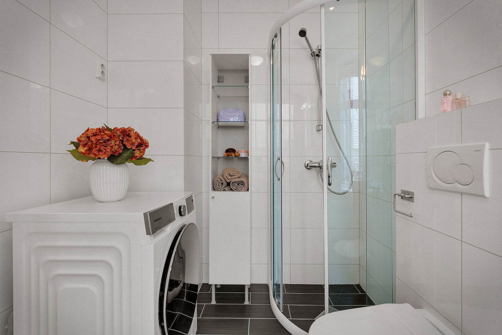 Utstyrt med veggehengt toalett, heldekkende servant, baderomsrinnredning, dusj og opplegg for både vaskemaskin og tørketrommel. Galleribilde