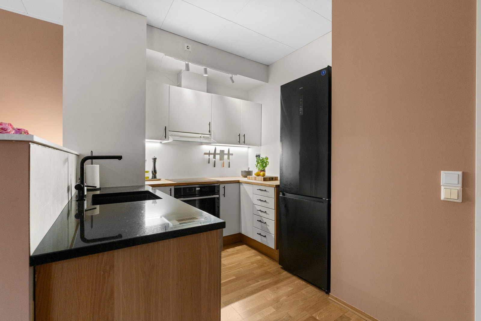 Delvis åpen kjøkkenløsning med god skap- og benkeplass. Kjøkkenet har en praktisk utforming og innredning med slette fronter, benkeplater i heltre eik og stein samt integrert oppvaskkum med ettgreps blandebatteri Galleribilde