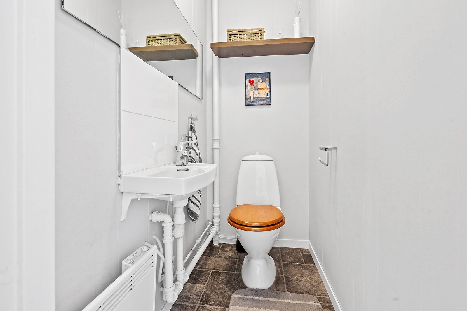 Separat toalettrom utstyrt med frittstående toalett og servant. Galleribilde