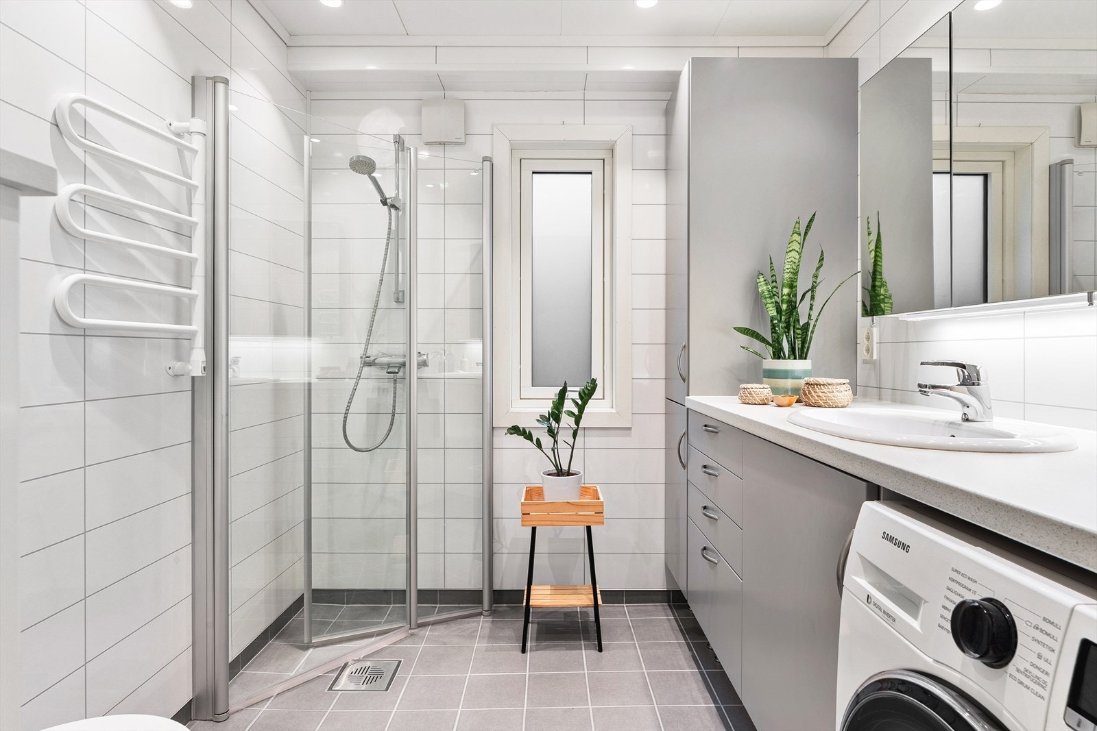 Badet er utstyrt med baderomsinnredning med nedfelt servant, vegghengt toalett, dusj og opplegg for vaskemaskin Galleribilde