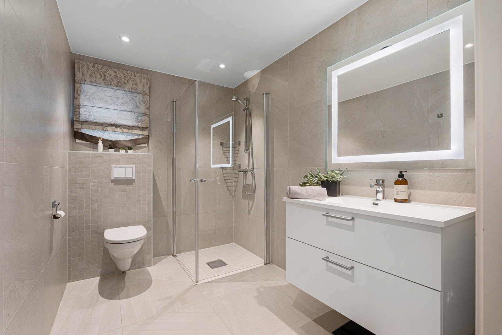 Stilfullt og flisbelagt baderom med downlights fra tak. Galleribilde