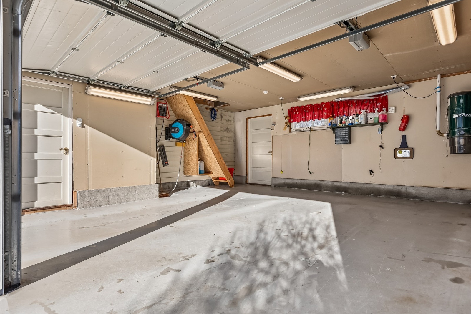 Stor dobbeltgarasje med god plass til oppbevaring på loft via direkte trapp. Det er en elbillader i høyre kjørefelt i garasjen. Galleribilde