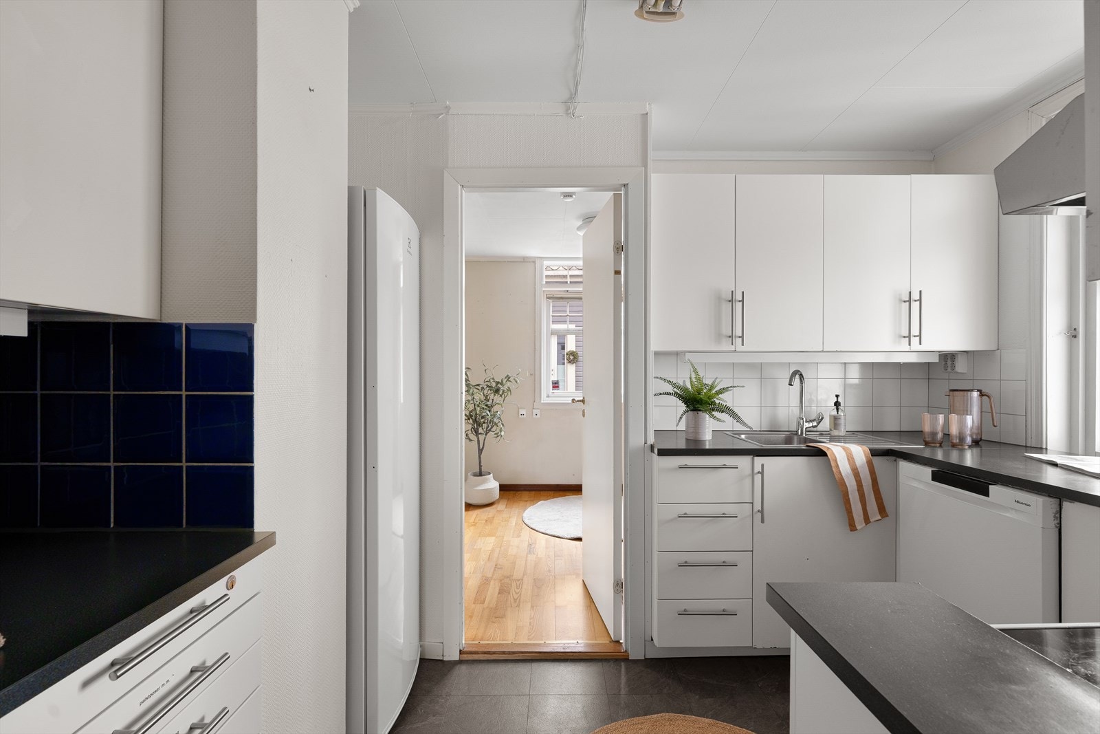 Kjøkken i hvit utførelse med sort laminert benkeplate og stålvask. Galleribilde