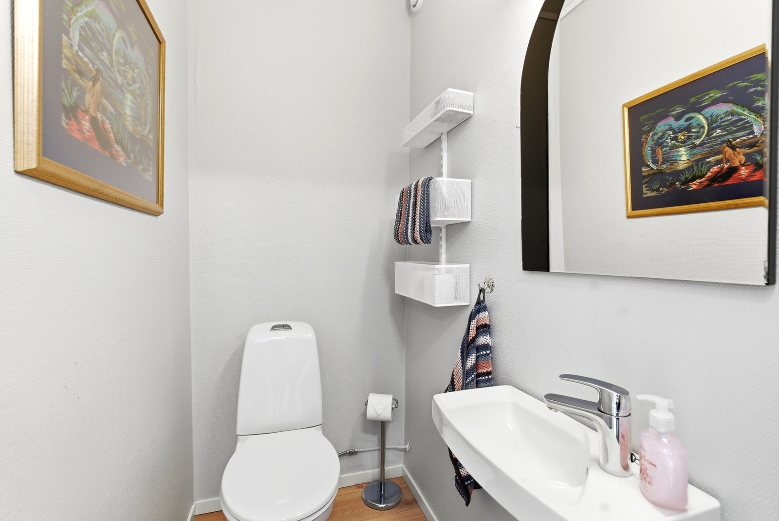 Toalettrom vegg-i-vegg med badet. Gulvstående toalett og vegghengt servant/speil. Galleribilde