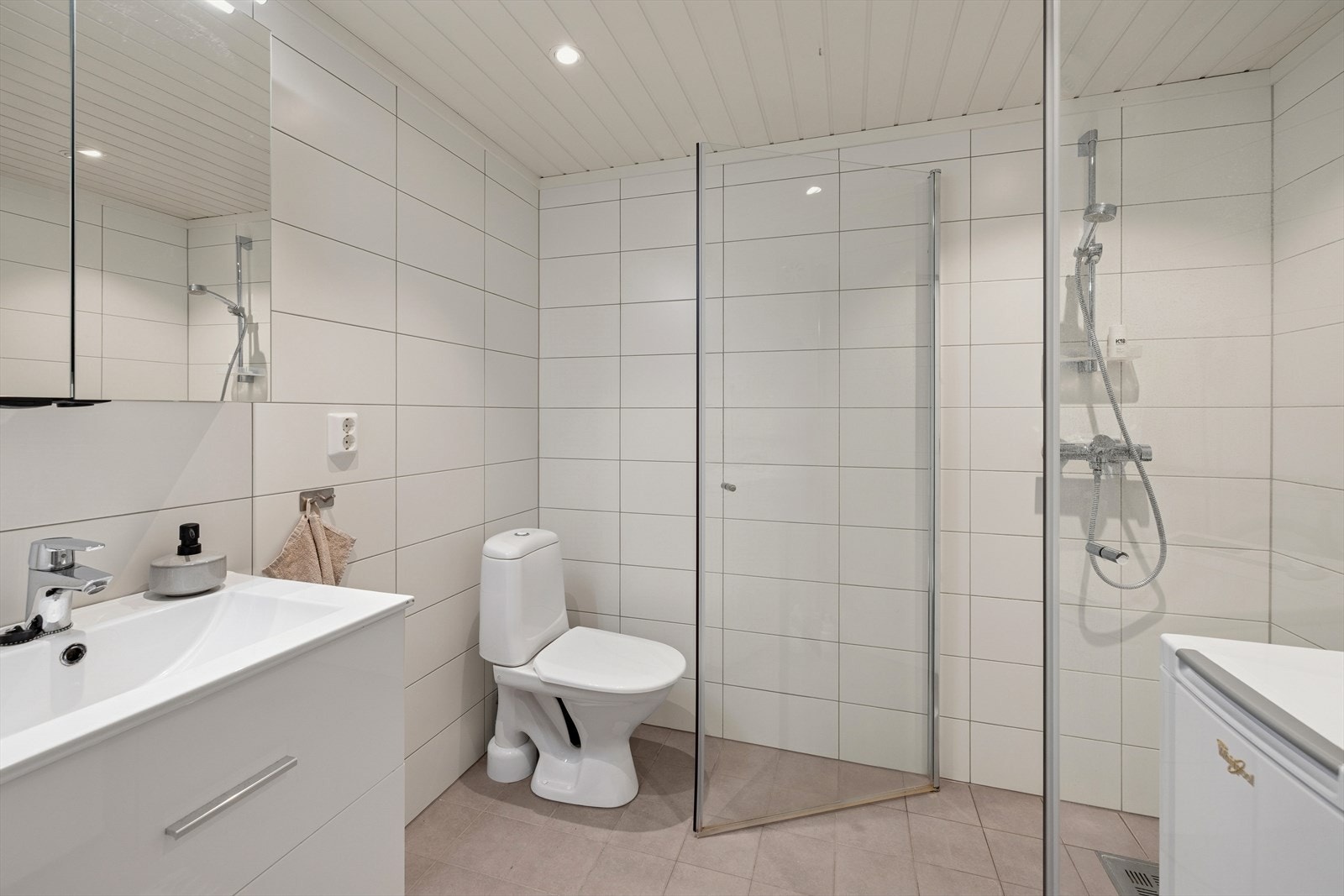 Badet i kjeller var nytt i 2018 og har fliser på vegger og gulv, samt panel i himlingen. Gulvet har gulvvarme. Badet er utstyrt med et gulvmontert toalett, servant med underskap, speil med tilhørende belysning og dusjvegger. Galleribilde