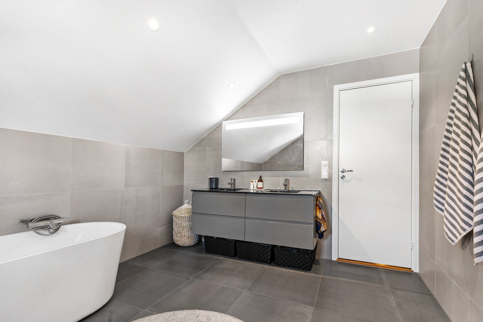 Speil med overlys og stikkontakt over servant. Badekar med vegghengt badekararmatur. Vegghengt toalett. Galleribilde