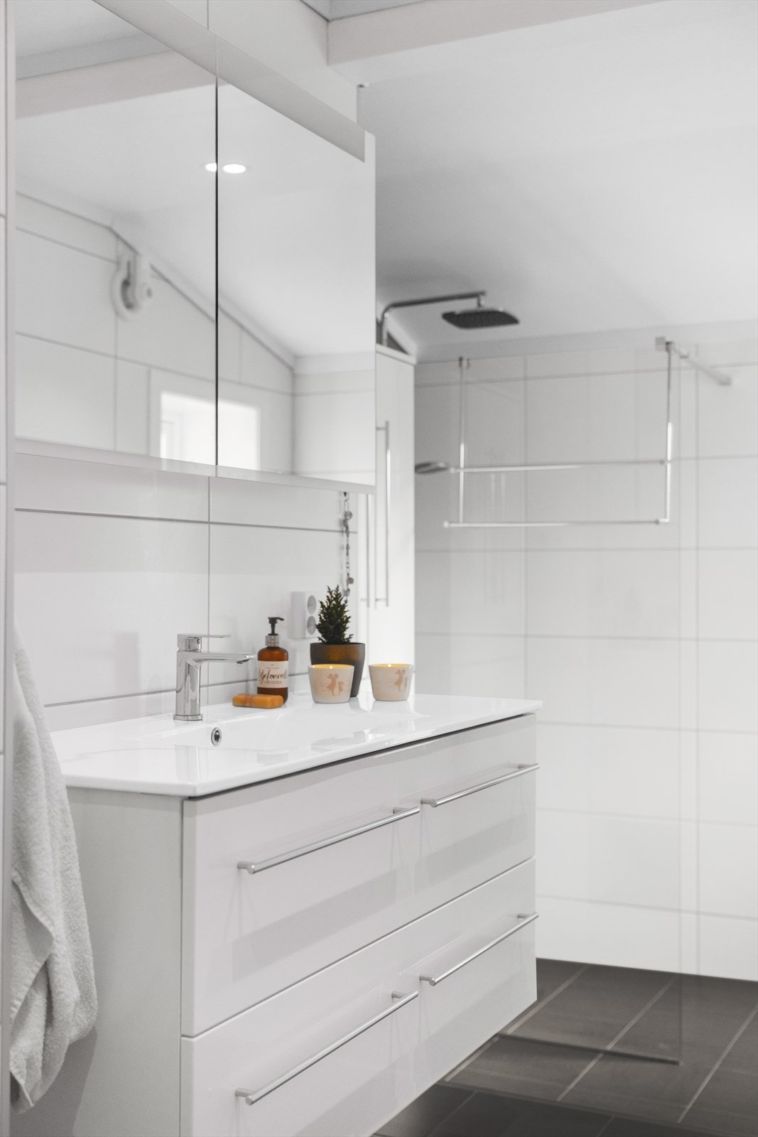 Baderommet er utstyrt med varmekabler, heldekkende servant over skuffeinnredning, speilskap, vegghengt skap og stort dusjhjørne Galleribilde