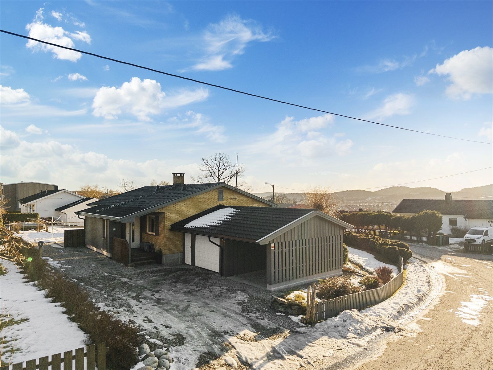 Tomten har gruset gårdsplass med gode parkeringsmuligheter i carport samt garasje. Her er det montert el-billader Galleribilde