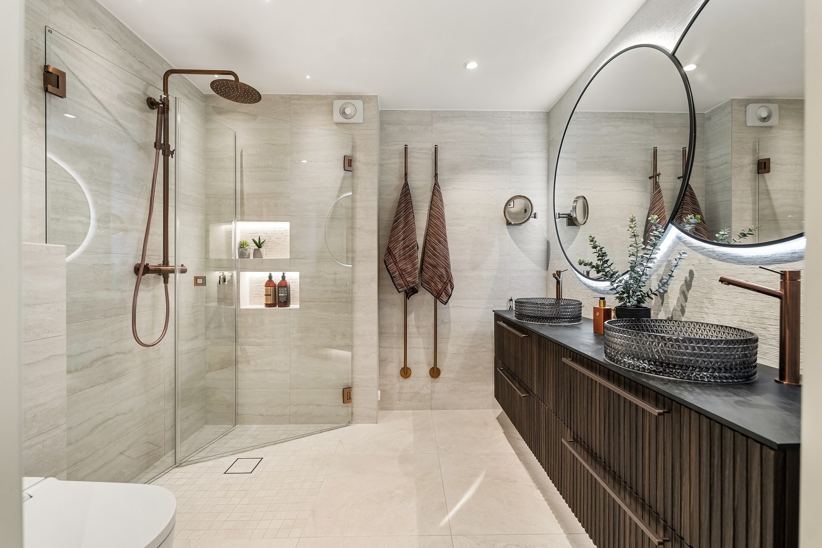 Badet fremstår som moderne og delikat med flislagte overflater på både vegger og gulv. Det er vegghengt dusjtoalett fra Geberit. Galleribilde