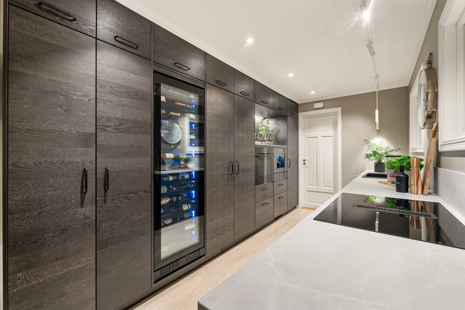 Benkeplaten er i laminat med nedfelt kum i kompositt. Kjøkkenet er utstyrt med integrerte hvitevarer som induksjonstopp, stekeovn, varmeskuff, oppvaskmaskin, kaffemaskin, vinskap samt kjøleskap. Galleribilde