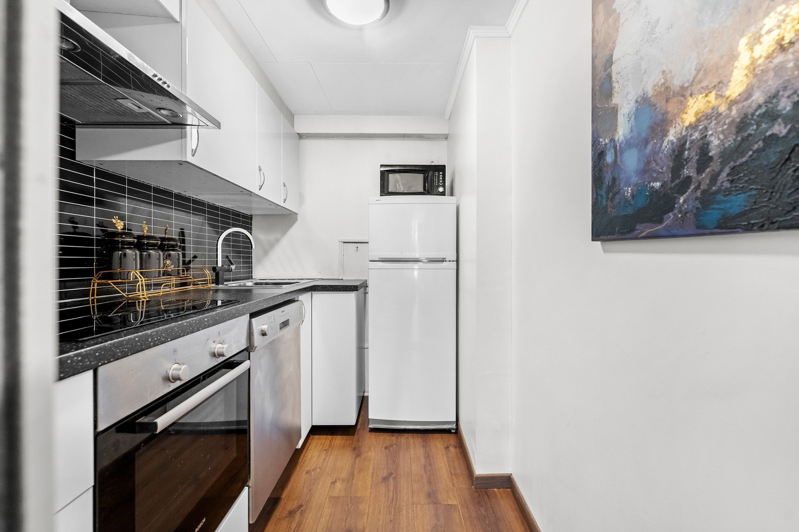 Hybel: Av hvitevarer medfølger integrert platetopp, komfyr og halvintegrert oppvaskmaskin. Det er avsatt plass til frittstående kjøleskap, og elektrisk ventilator er montert over kokesonen. Galleribilde