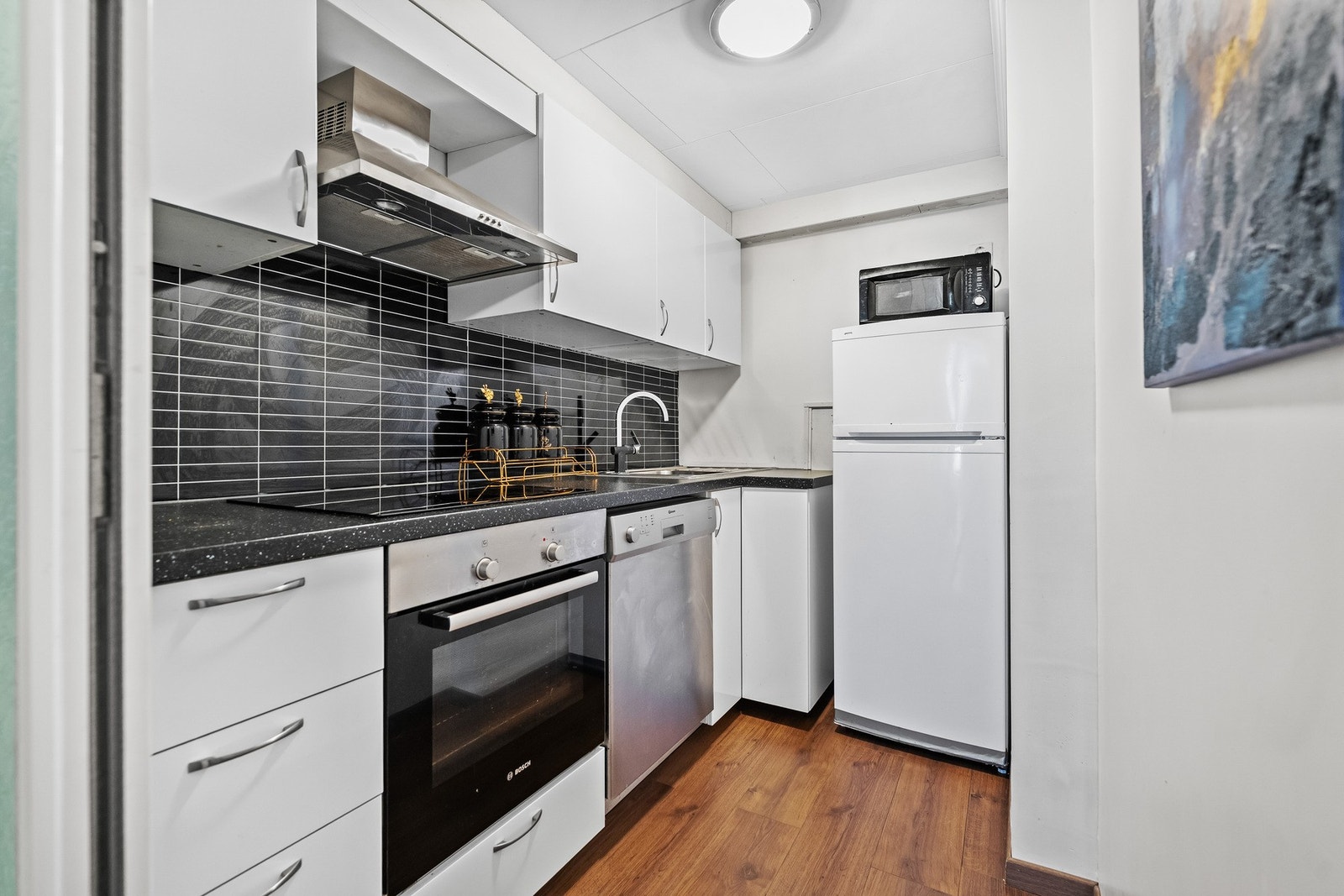 Hybel: Separat kjøkken fra 2015 med innredning i hvite, slette fronter. Benkeplaten er av laminat med nedfelt vaskekum. Galleribilde