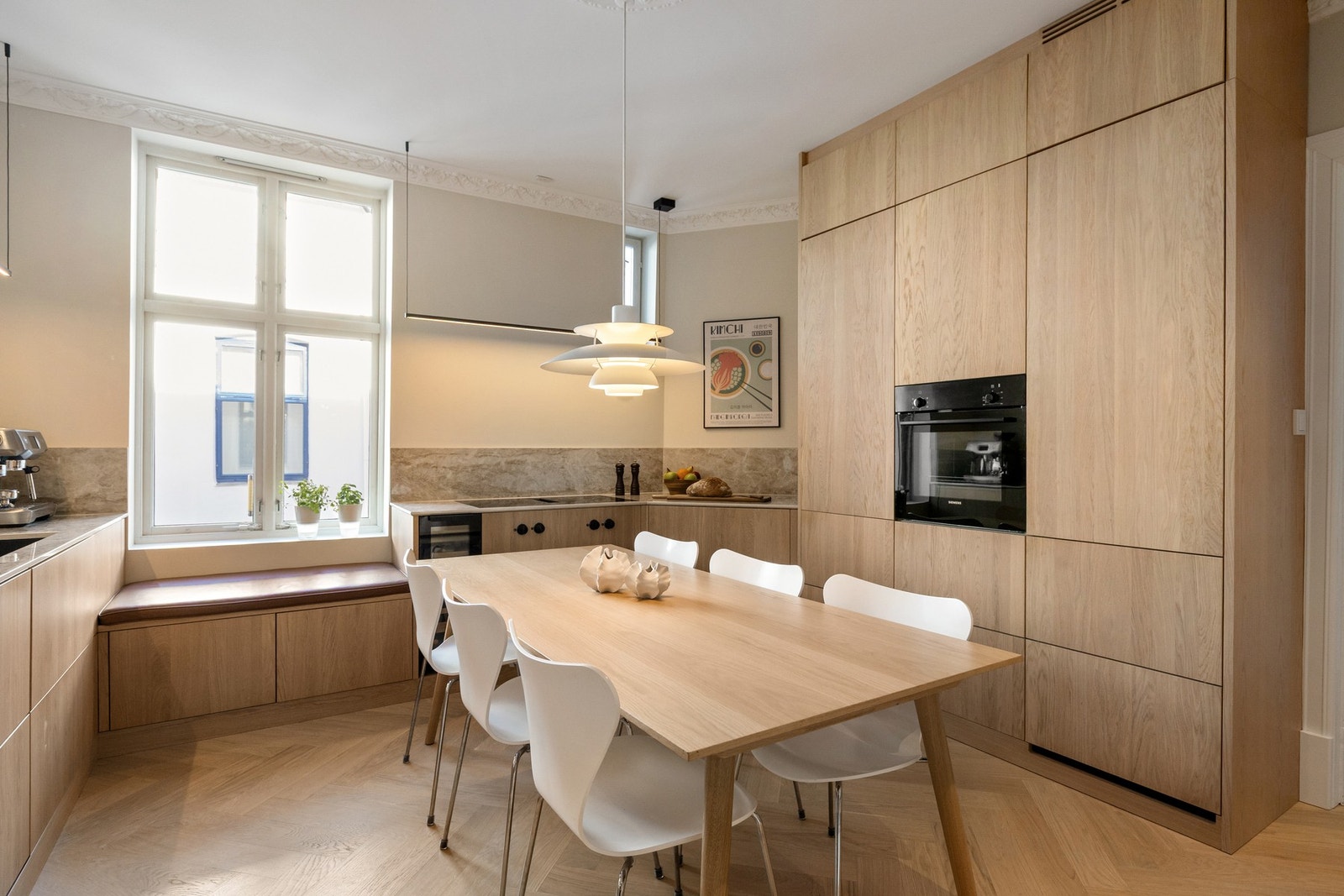 Stilrent kjøkken fra Drømmekjøkken. Oppusset i 2022 og innredet med slette fronter i eik og Dekton benkeplater. Galleribilde