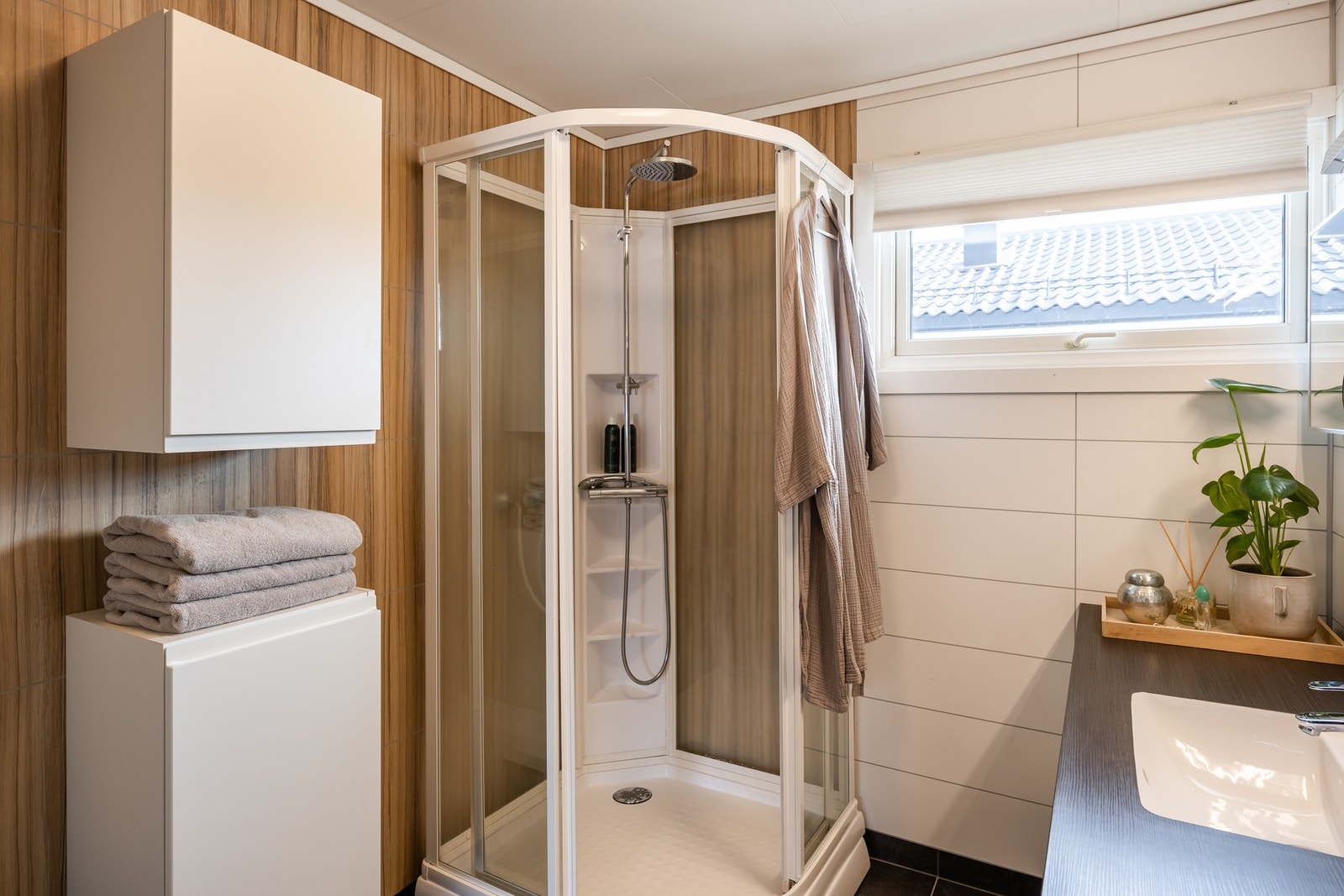 Badet er utstyrt med flislagt gulv, våtromsplater og dusjkabinett. Galleribilde