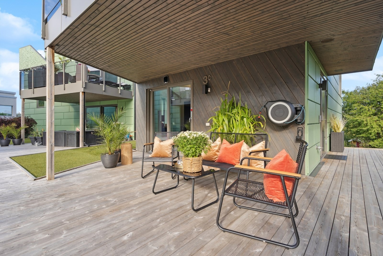 Den overbygde terrassen på 28 kvm flukter mot inngangspartiet samt mot fellesarealer mellom husene (kunstgress) og øvrige plenområder. Galleribilde