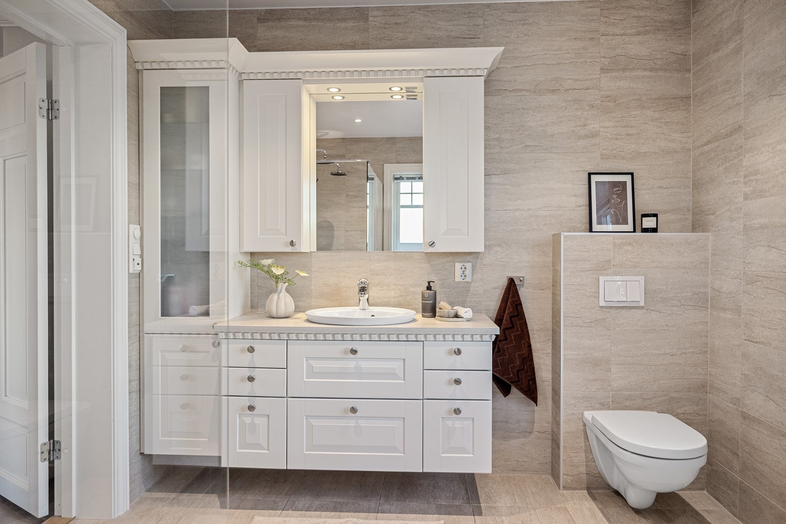 Servantskapet med speil, to veggskap og et praktisk høyskap gir rikelig med oppbevaringsplass. Det vegghengte klosettet understreker den nydelige stilen. Galleribilde