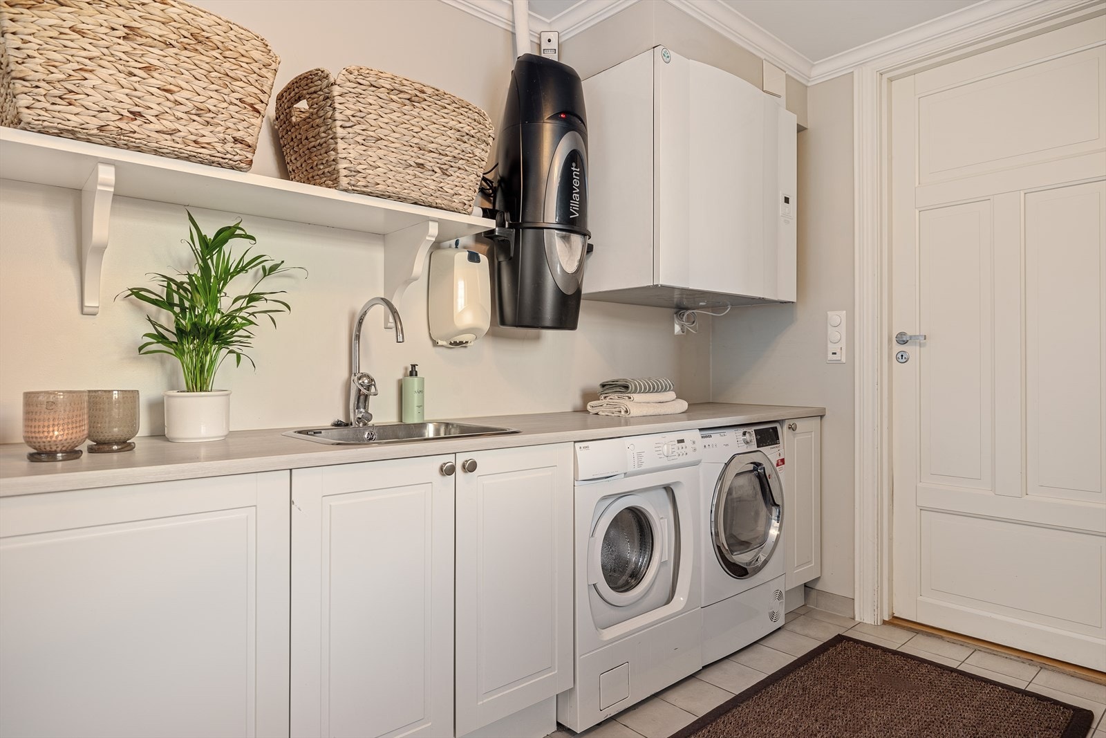 Rommet er innredet med flere oppbevaringsskap som gir god plass til både tekstiler og utstyr, samt en praktisk benkeplate med skyllekum. Her finner du også opplegg for vaskemaskin, samt en praktisk hylleløsning som gjør organiseringen enkel. Galleribilde