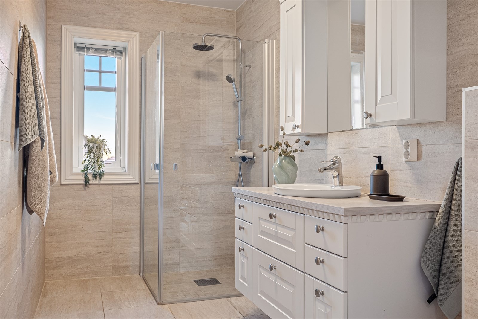 Det andre badet er også lekkert flislagt og holder en svært god standard. Rommet er innredet med et flott dusjhjørne med glassvegger, servantskap med speil, to praktiske overskap og et stilrent vegghengt klosett. Galleribilde