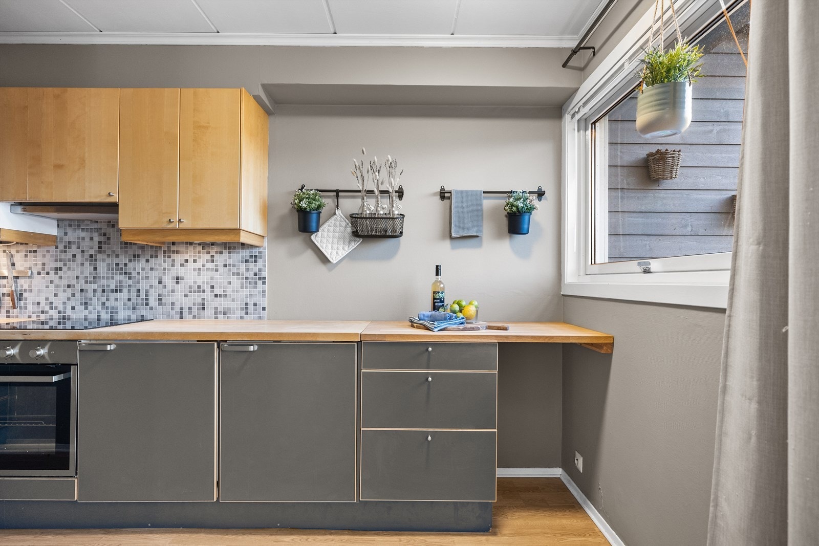 Kjøkkeninnredningen har glatte fronter som gir et rent og moderne uttrykk, og benkeplatene i laminert heltre tilfører rommet en lun kontrast samt gode og romslige arbeidsflater. Galleribilde