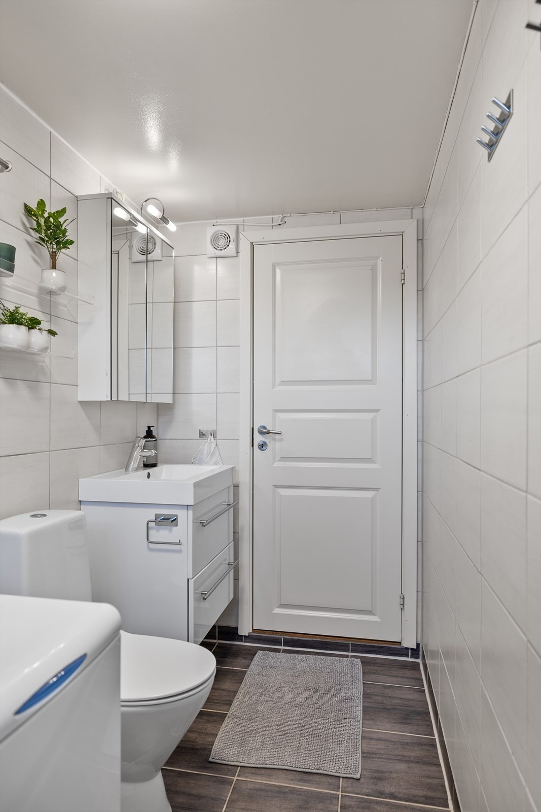 Rommet er praktisk og oversiktlig innredet med baderomsinnredning med nedfelt servant, toalett og dusjhjørne med dusjvegger. I tillegg er det opplegg for vaskemaskin, noe som gir en effektiv og plassbesparende løsning i hverdagen Galleribilde