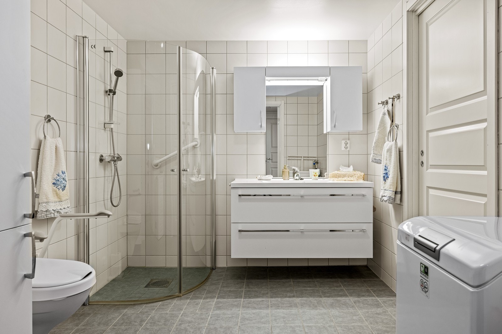 Badet er praktisk innredet med dusjhjørne, veggfestet toalett og opplegg for vaskemaskin. Galleribilde