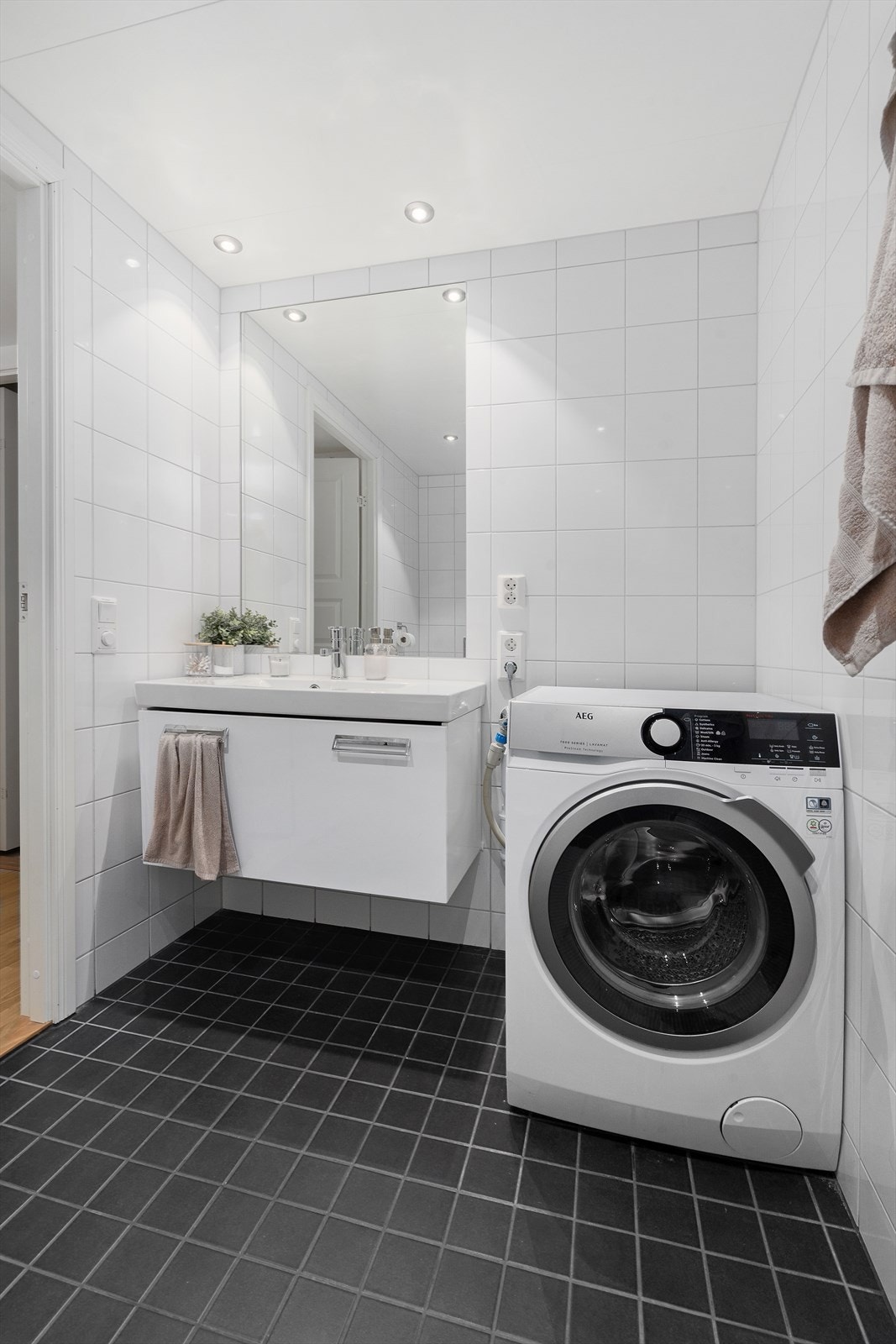 Klassisk baderomsinnredning med slette fronter, servant og speil. Badet er utstyrt med vegghengt toalett og dusjhjørne. Galleribilde