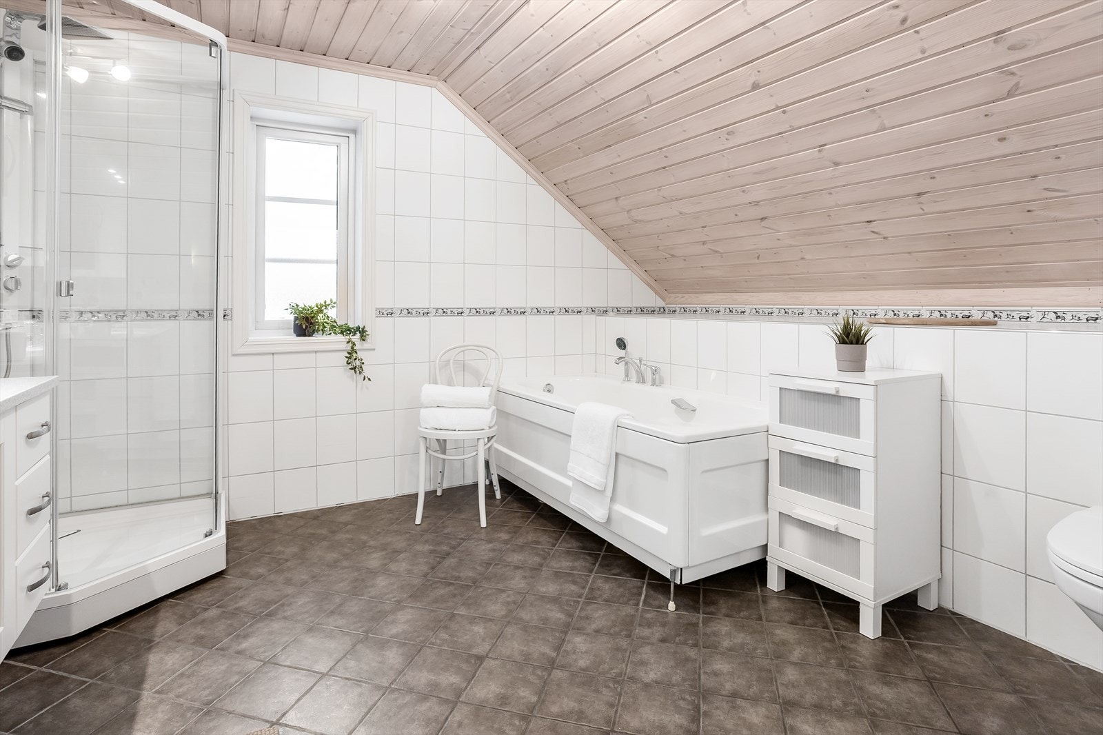 Badet er innredet med hvit servantinnredning med dobbelservant, speil med belysning, toalett, badekar og dusjkabinett. Galleribilde