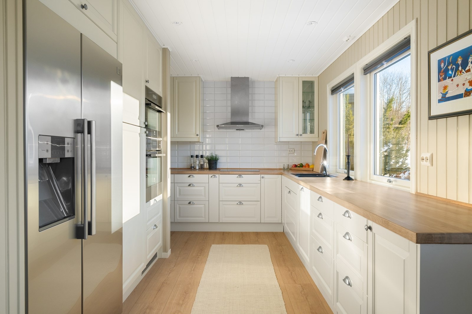 Lyst og fint kjøkken med benkeplate i eik - her får man godt med skap- og benkeplass Galleribilde