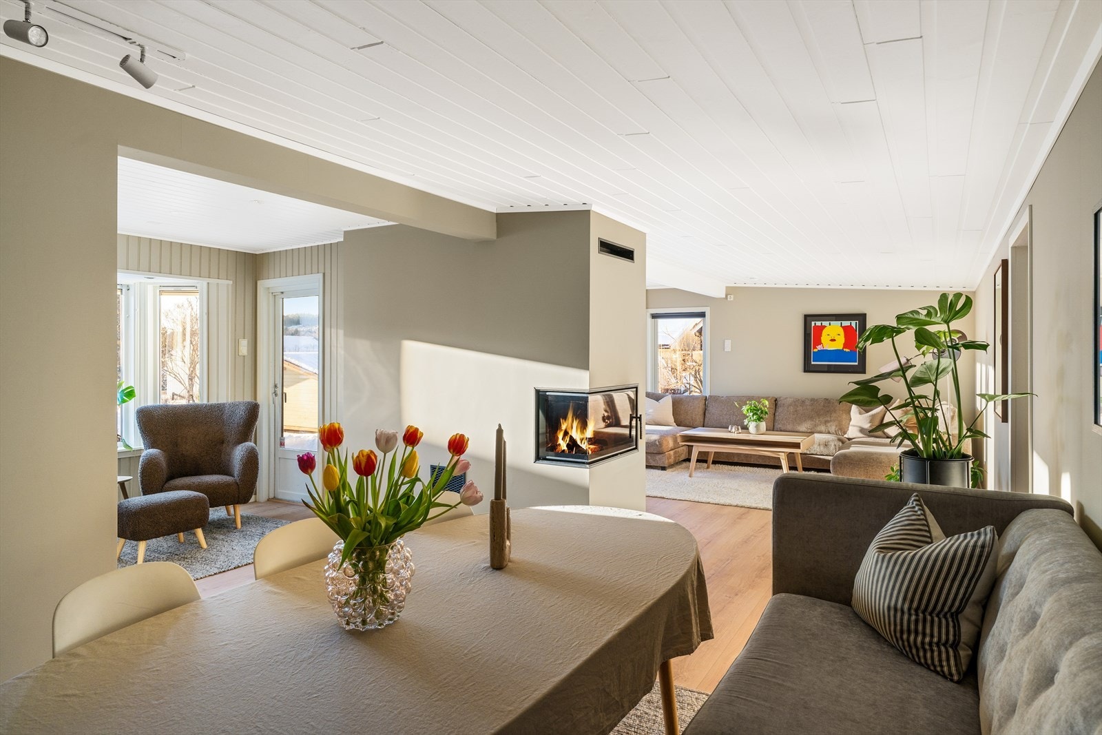 Peisen er plassert sentralt i rommet og gir både effektiv oppvarming og et naturlig samlingspunkt. Galleribilde