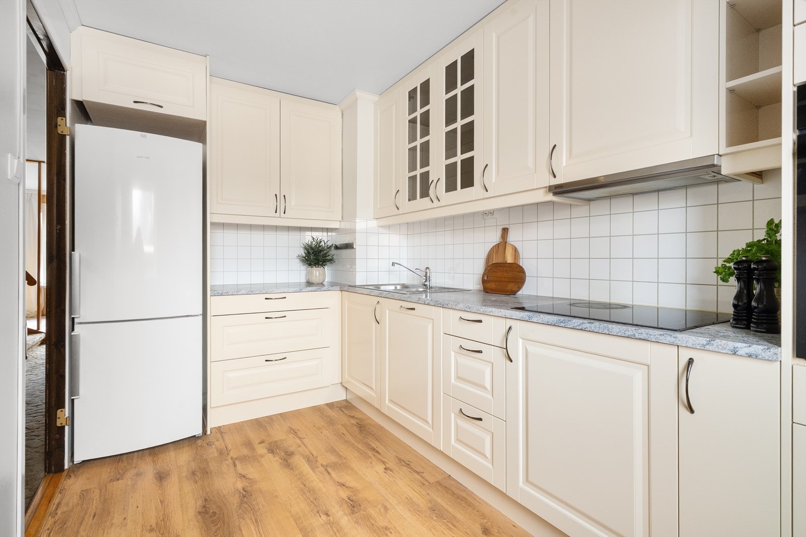 Kjøkken har hvit innredning fra 2009 med profilerte fronter og laminert benkeplate med fliser over Galleribilde