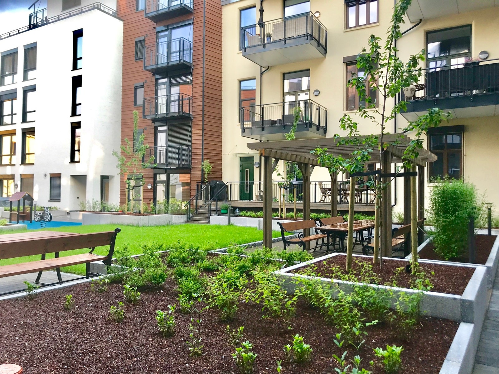 Stort grønt atrium som er felles uteareal med sitteplasser for beboerne Galleribilde