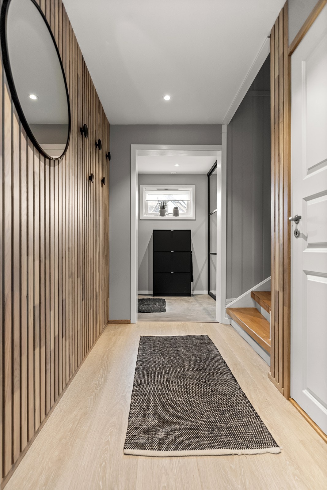 Hallen har en moderne spilevegg og leder videre inn i boligens første etasje. Galleribilde