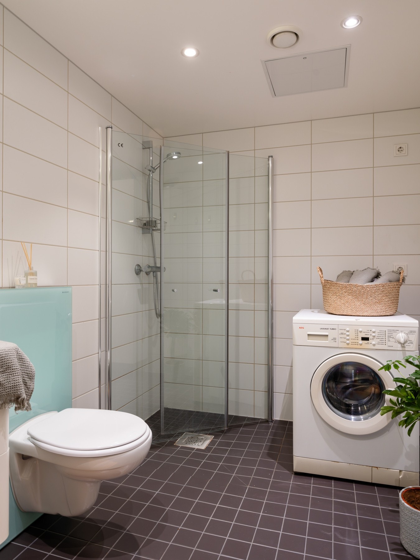 Badet er innredet med vegghengt toalett og dusjhjørne med svingbare glassdører som frigjør plass på gulvet. Det er også opplegg for vaskemaskin og plass til tørketrommel. Galleribilde