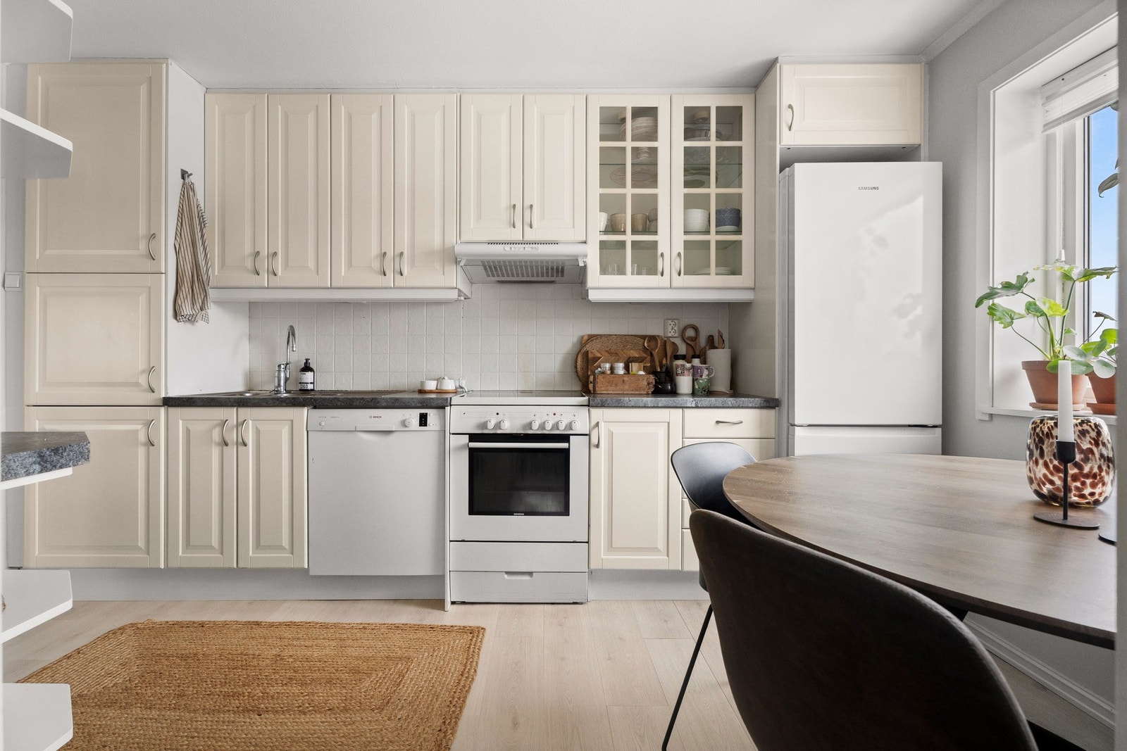 Kjøkkenet fremstår stilrent med profilerte fronter, fliser over benk og overskap helt opp til himling som gir maksimal lagringsplass. Galleribilde