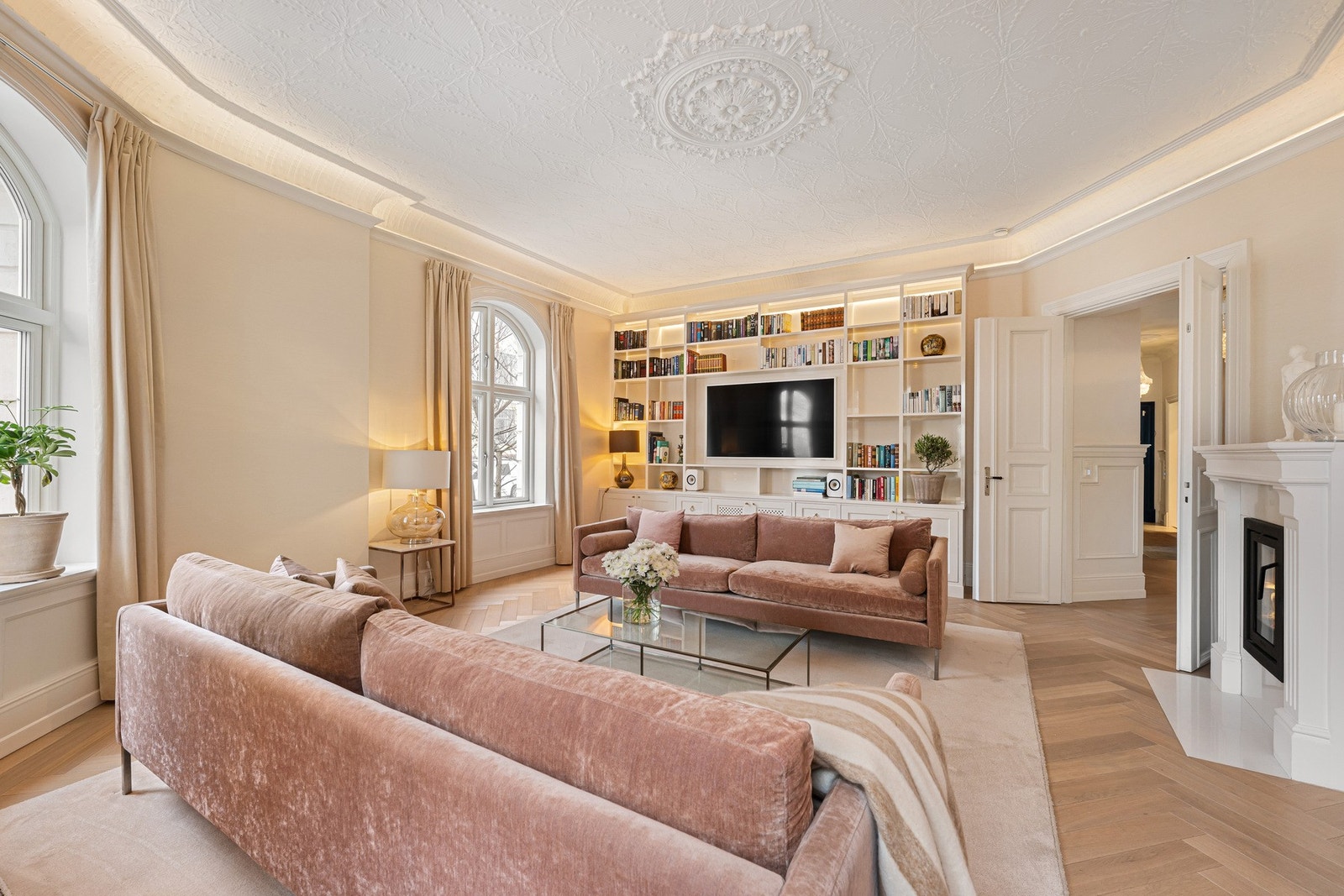 Lys stue med fiskebensparkett og dekorative himlinger som gir en elegant romfølelse. Galleribilde