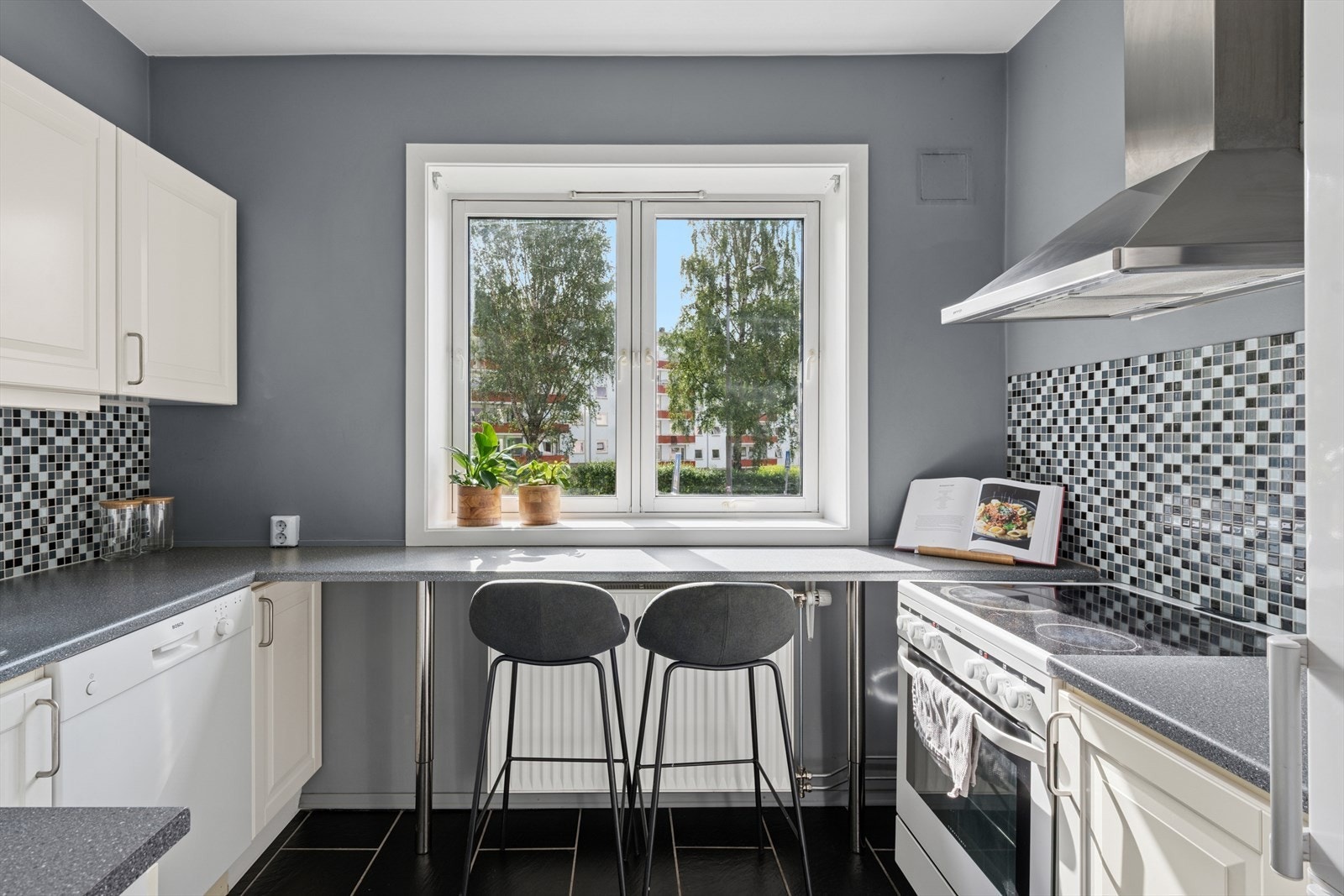 Kjøkkeninnredningen fra 2011 med profilerte malte fronter, laminat benkeplate med nedfelt rustfri kum, mosaikk på vegg over benk og ventilator med kullfilter. Opplegg for oppvaskmaskin og nisje i innredning for kjøle/fryseskap Galleribilde