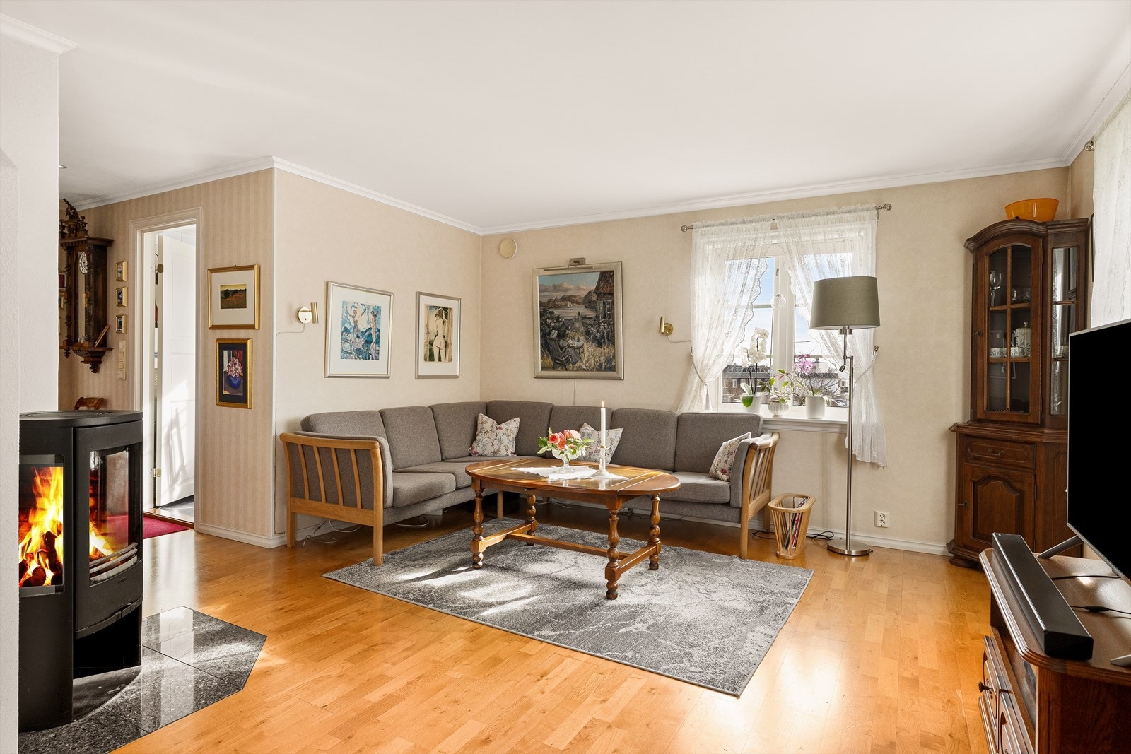 Stuen er pent innredet med parkett på gulv og lys tapet på vegger. Galleribilde