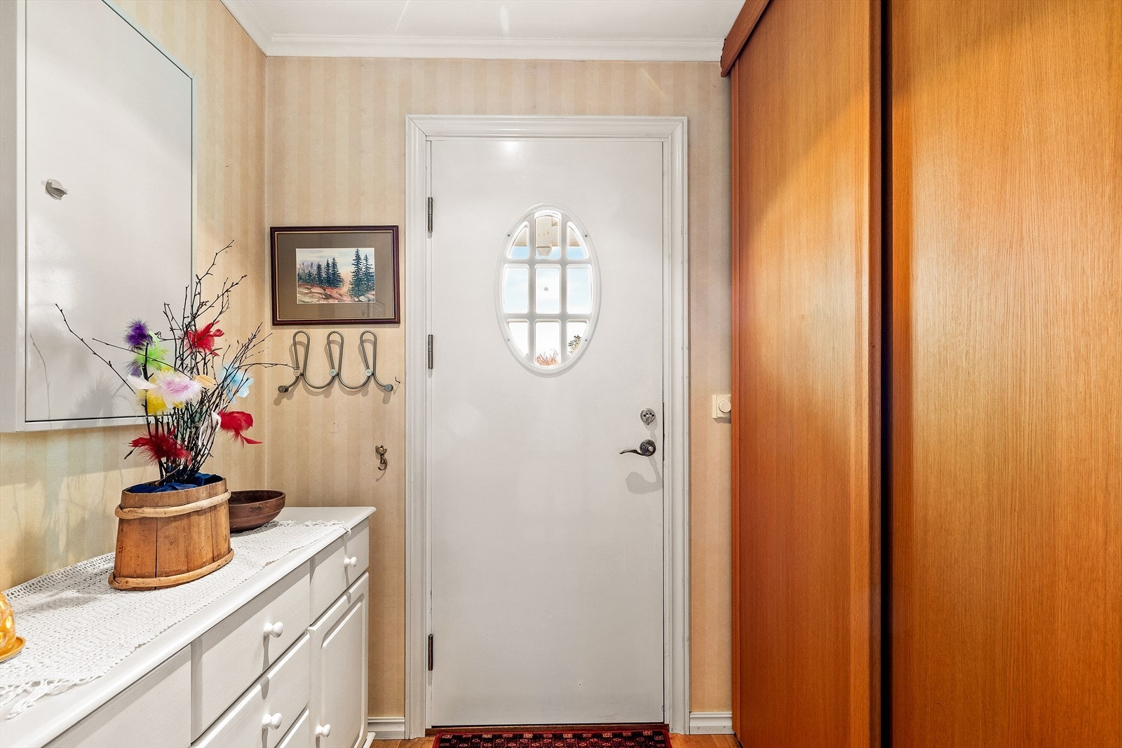 Man ankommer boligen fra et pent overbygget inngangsparti inn til en, innbydende hall med god plass til oppbevaring av klær og sko i skyvedørsgarderobe. Galleribilde