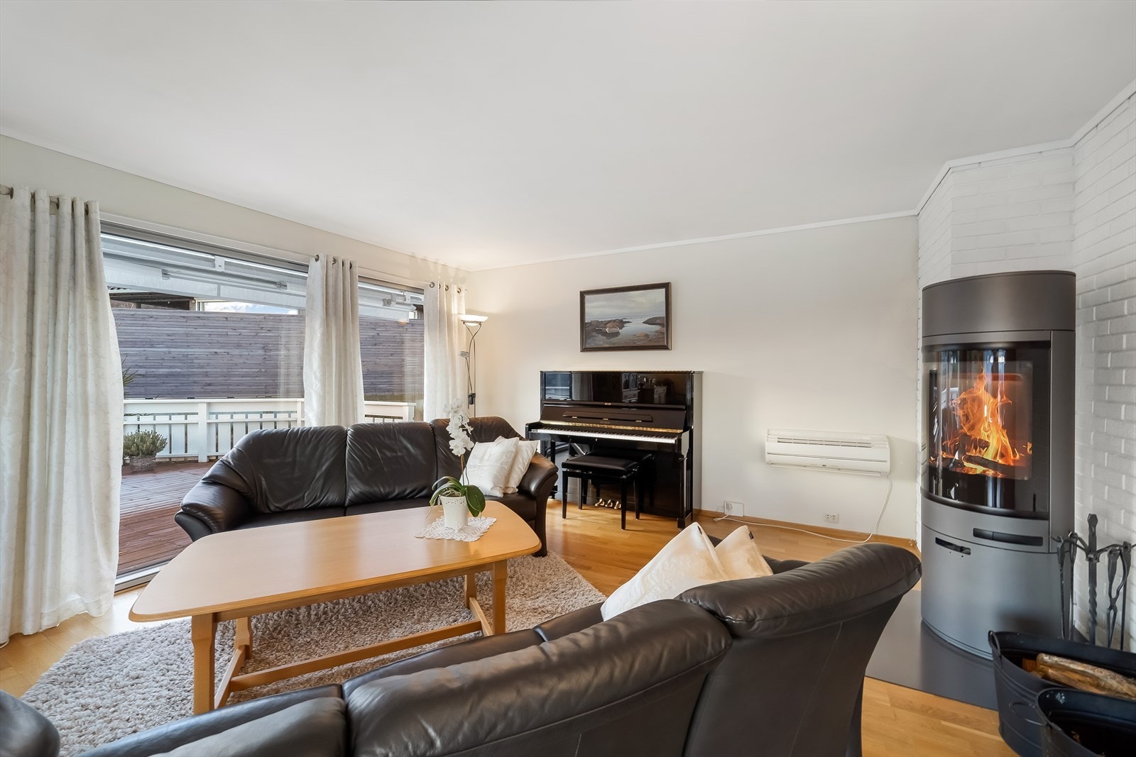 I hjørnet står en moderne vedovn som varmer godt og skaper stemning på kalde dager. Varmepumpe montert på vegg. Galleribilde