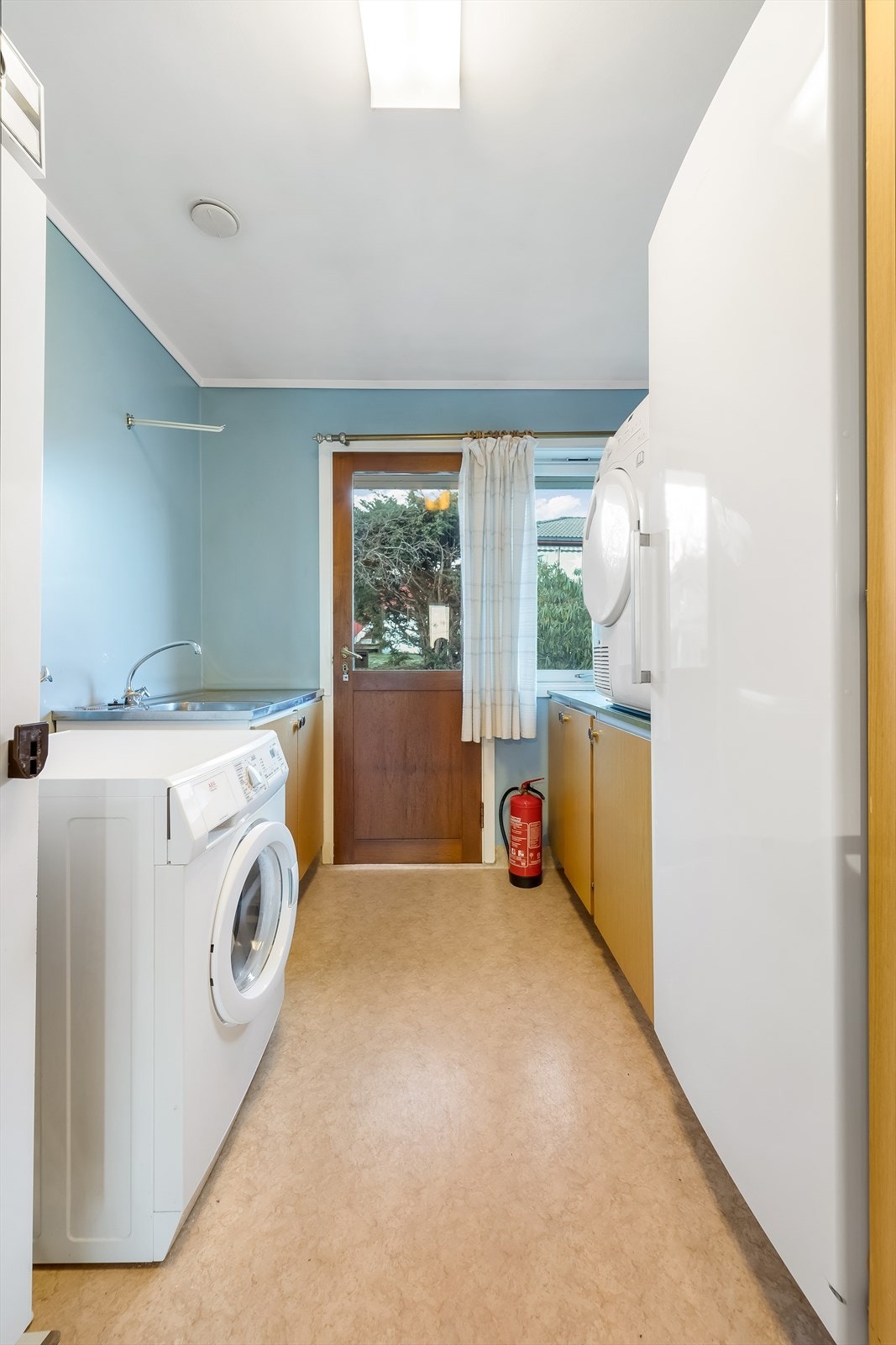 Vaskerom med utslagsvask og direkte adkomst ut til bakhagen. En praktisk løsning med mulighet for tørking av klær på stativ ute. Galleribilde