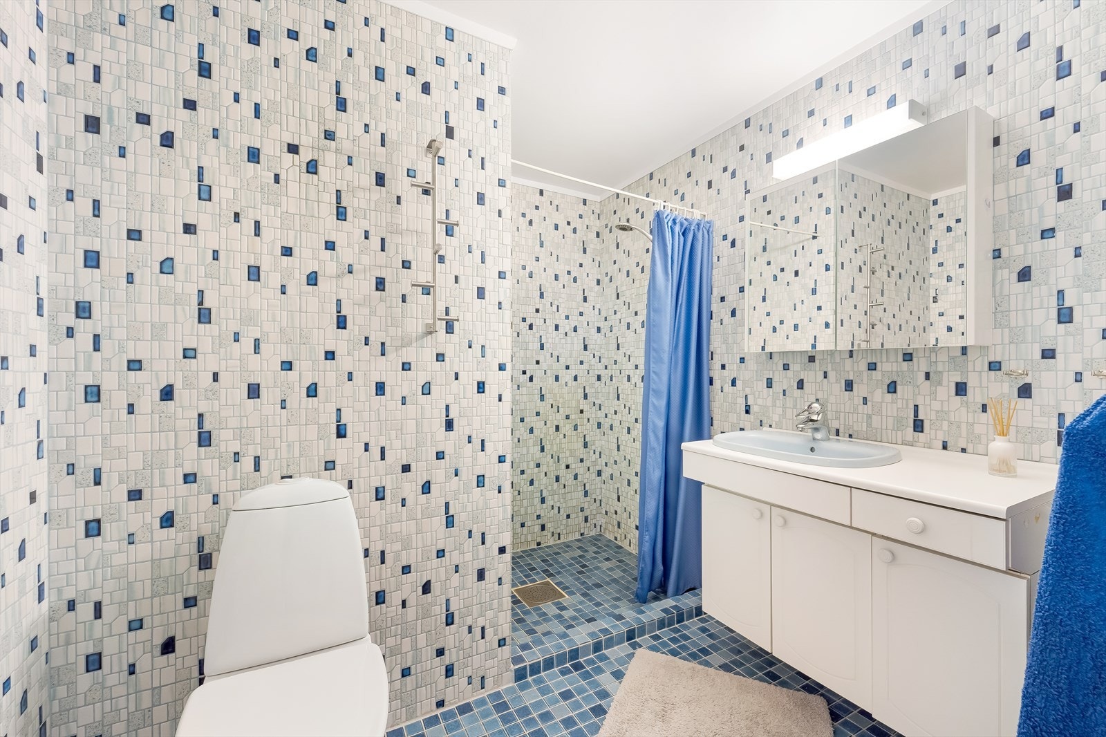 Bad i underetasjen med fliser på gulv og vegger. Varmekabler i gulv. Innredet med baderomsinnredning, toaett og dusjløsning med forheng. Galleribilde