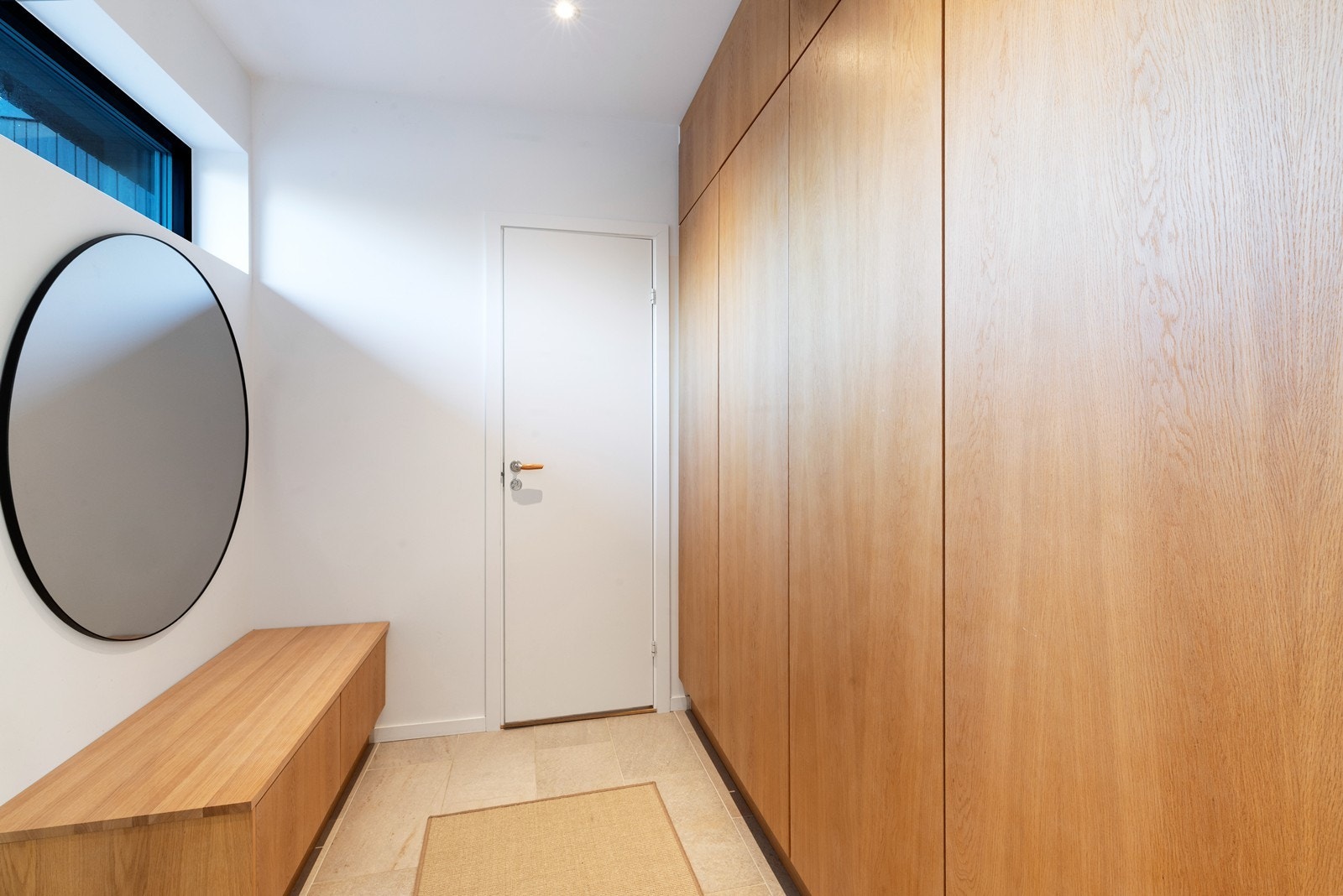 Gang med plassbygget skap og benk i samme utførelse som kjøkken og baderomsinnredning. Galleribilde