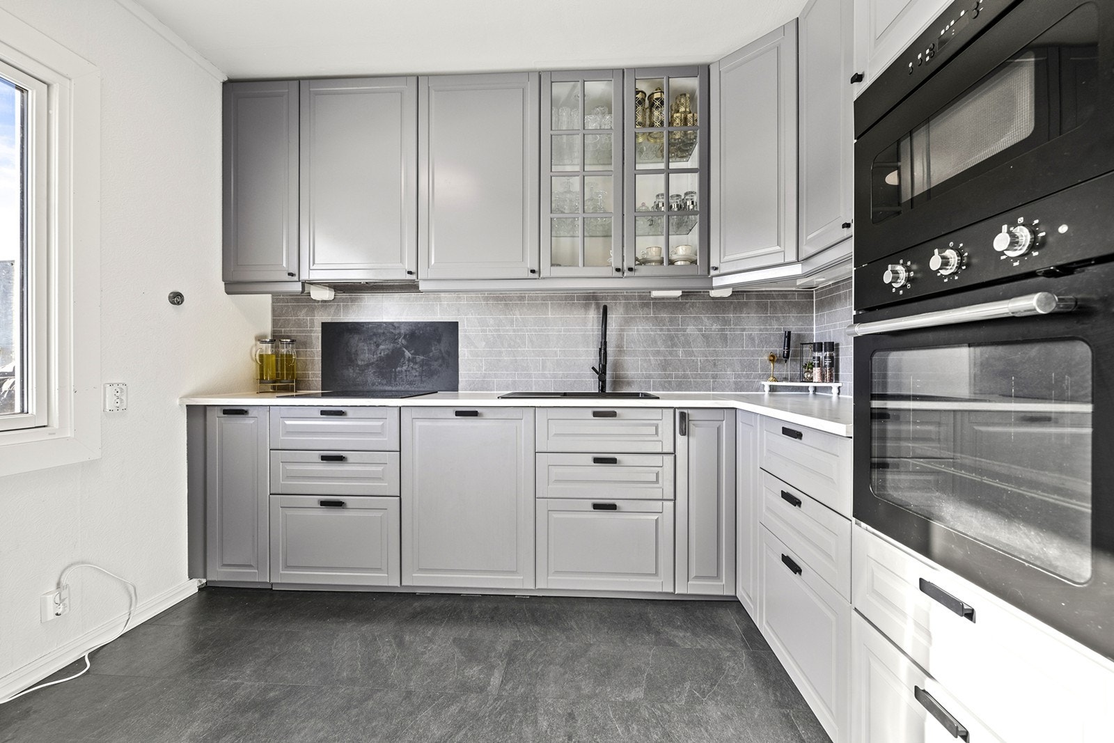 Grå kjøkkenfronter og lys benkeplate gir et stilrent uttrykk. Galleribilde